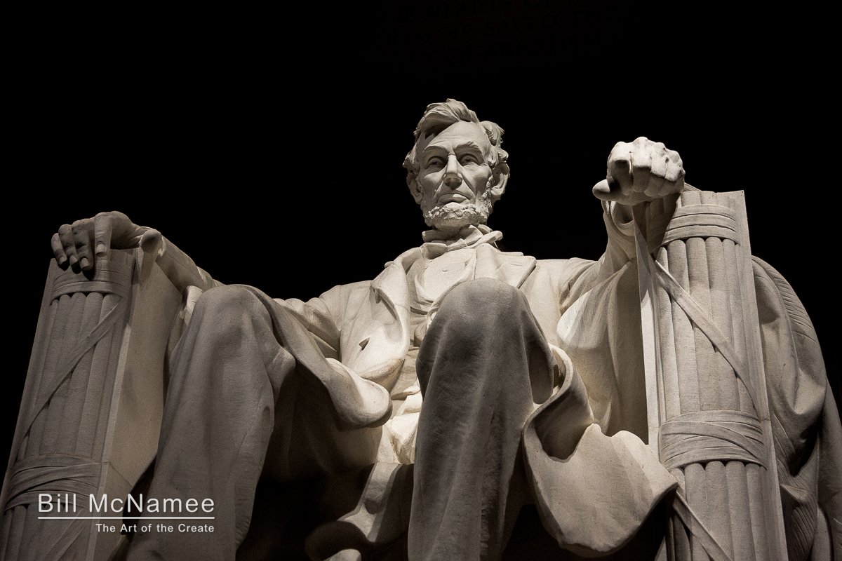 Abraham Lincoln seated in the Lincoln Memorial beneath dramatic nighttime lighting.