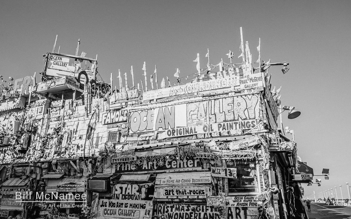 Ocean Gallery storefront on the Ocean City Maryland boardwalk photographed in black and white with strong sunlight and deep shadows.