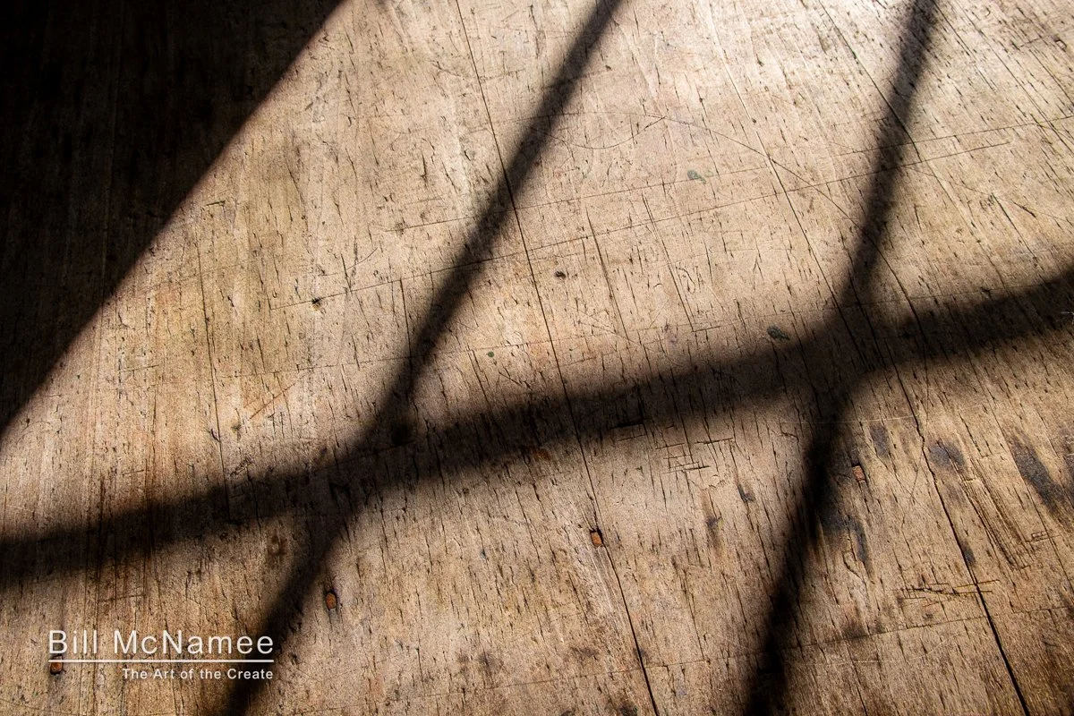 Shadows framing period wooden flooring inside a Colonial Williamsburg structure.