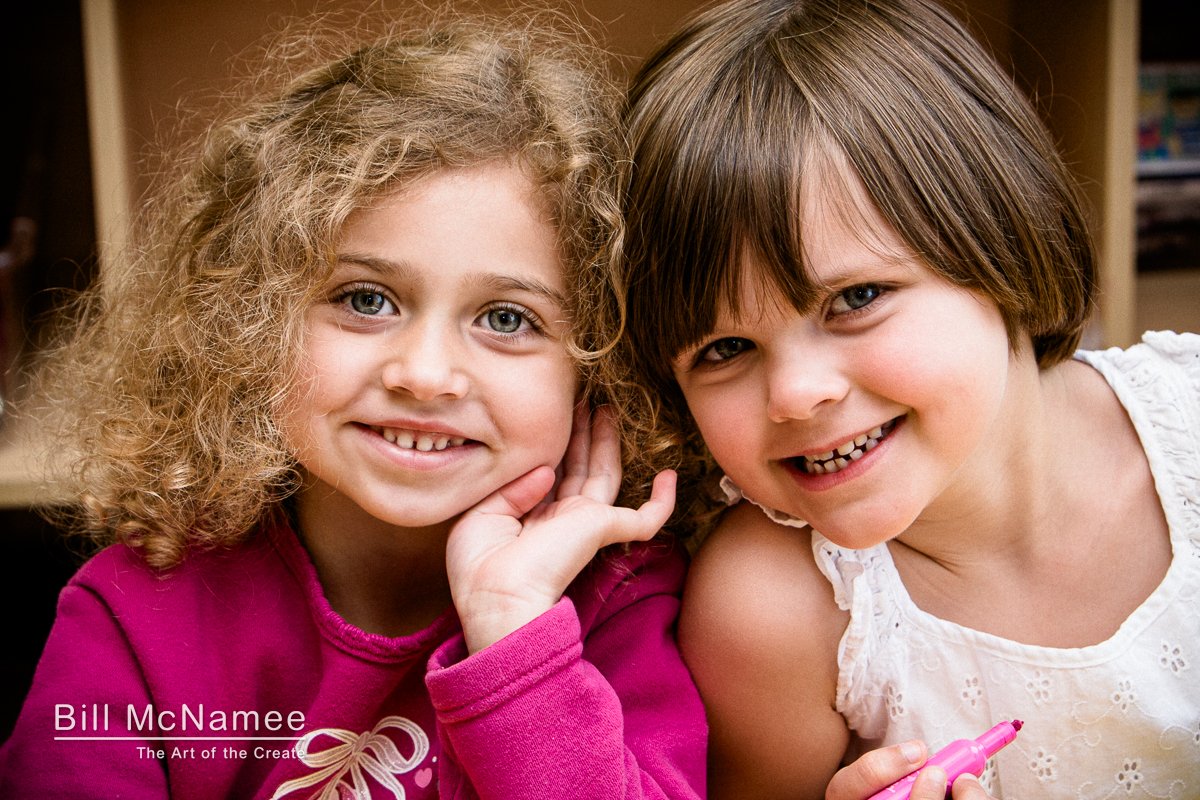 Two young girls share a moment together during a candid daycare portrait session.