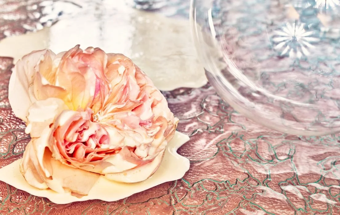 Pink and cream-colored rose with white chocolate on a decorative tablecloth.