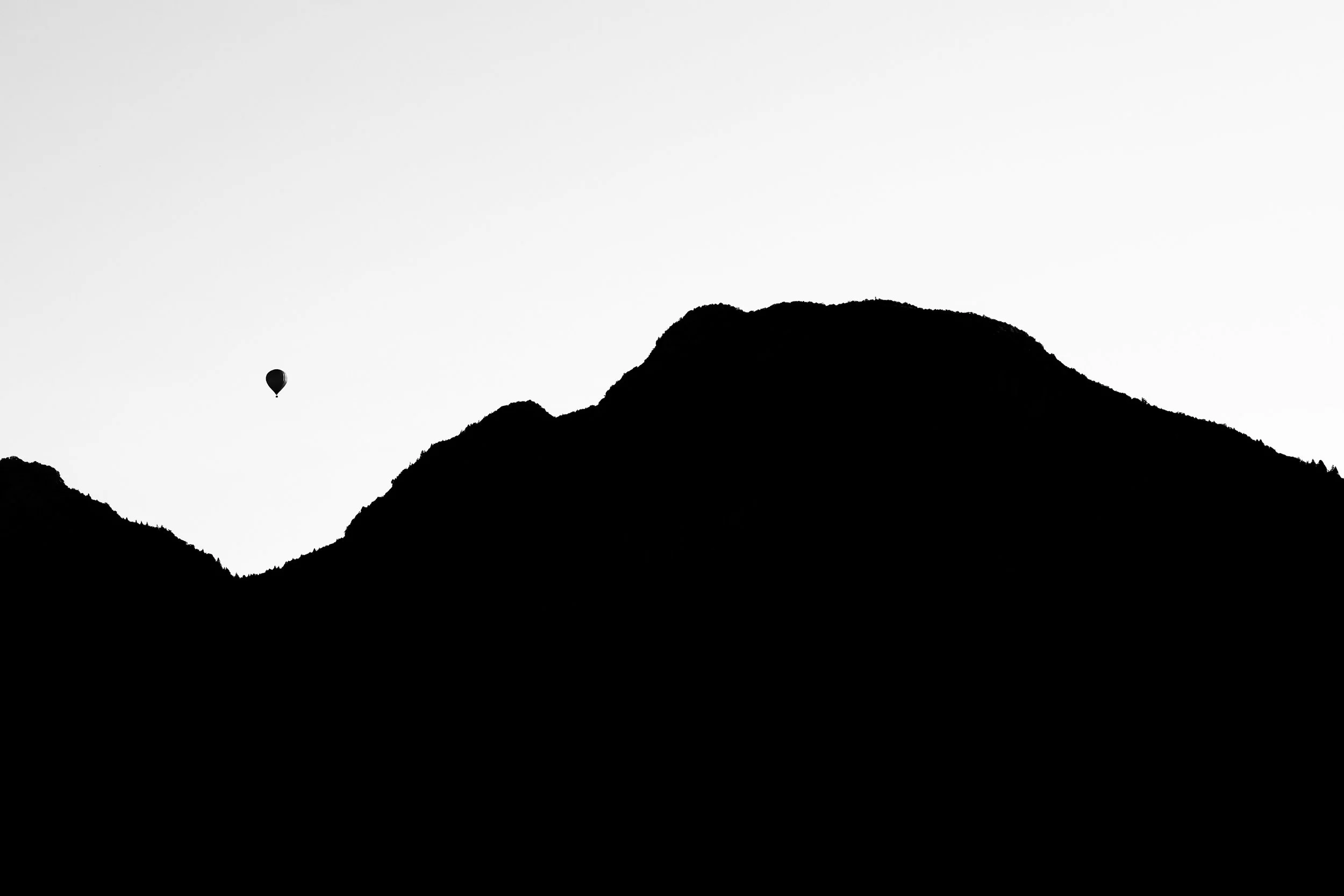Schwarz-weiße Silhouette von Bergen mit Heißluftballon im Himmel