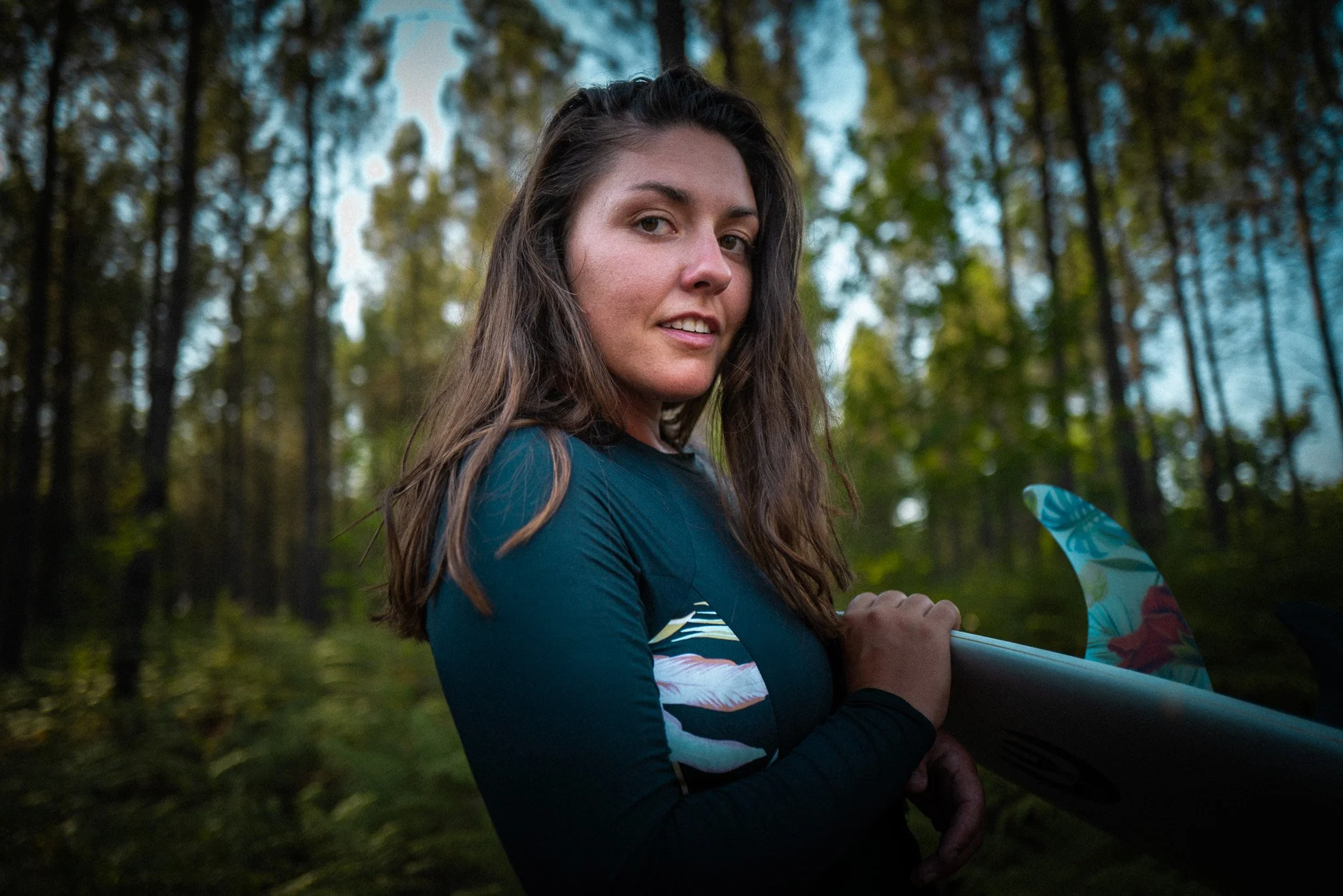 Junge Frau mit Surfbretter im Wald
