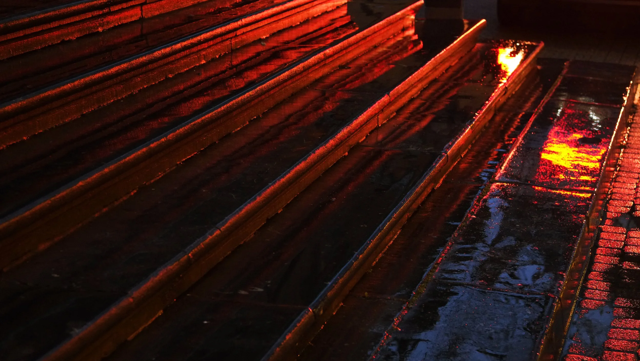 Nasse, glühende Eisenbezitze bei Sonnenuntergang, die reflektieren, in warmen orangenen und roten Tönen.