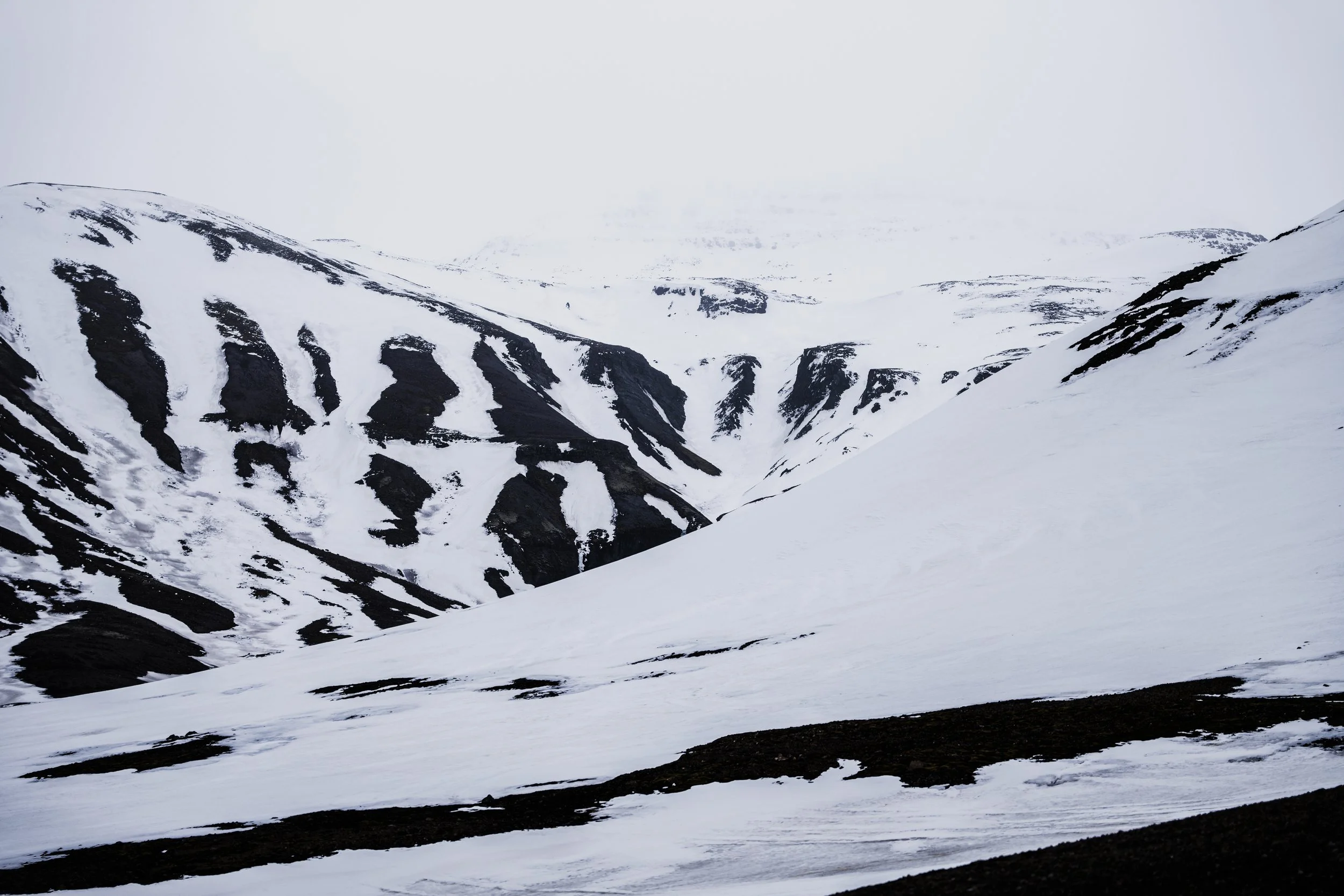 Schneebedeckte Berge mit schwarzen Felsen und Schnee im winterlichen Hochland.