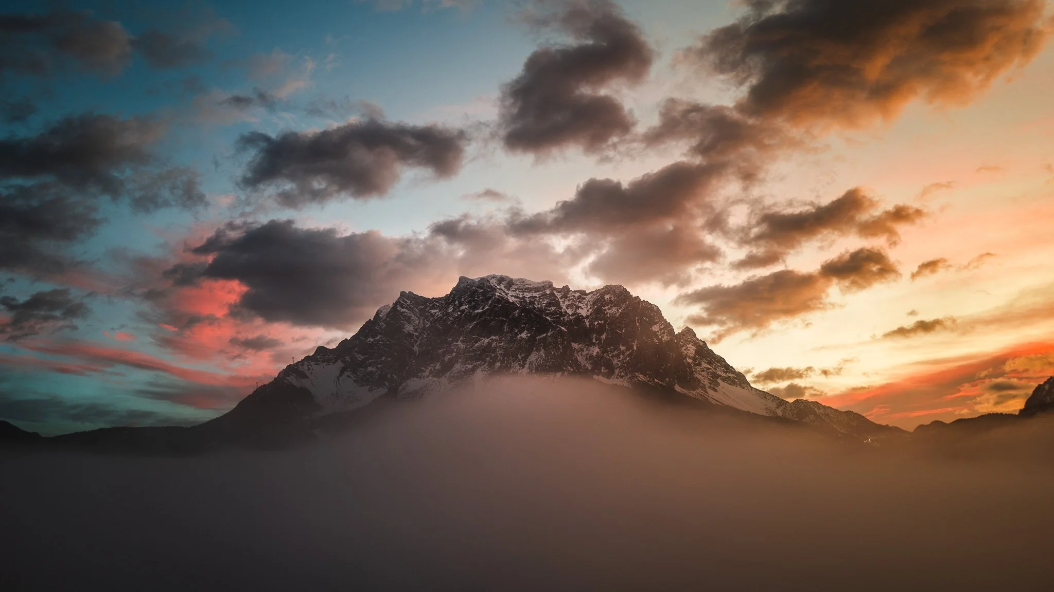 Berg bei Sonnenuntergang mit Wolken und Nebel