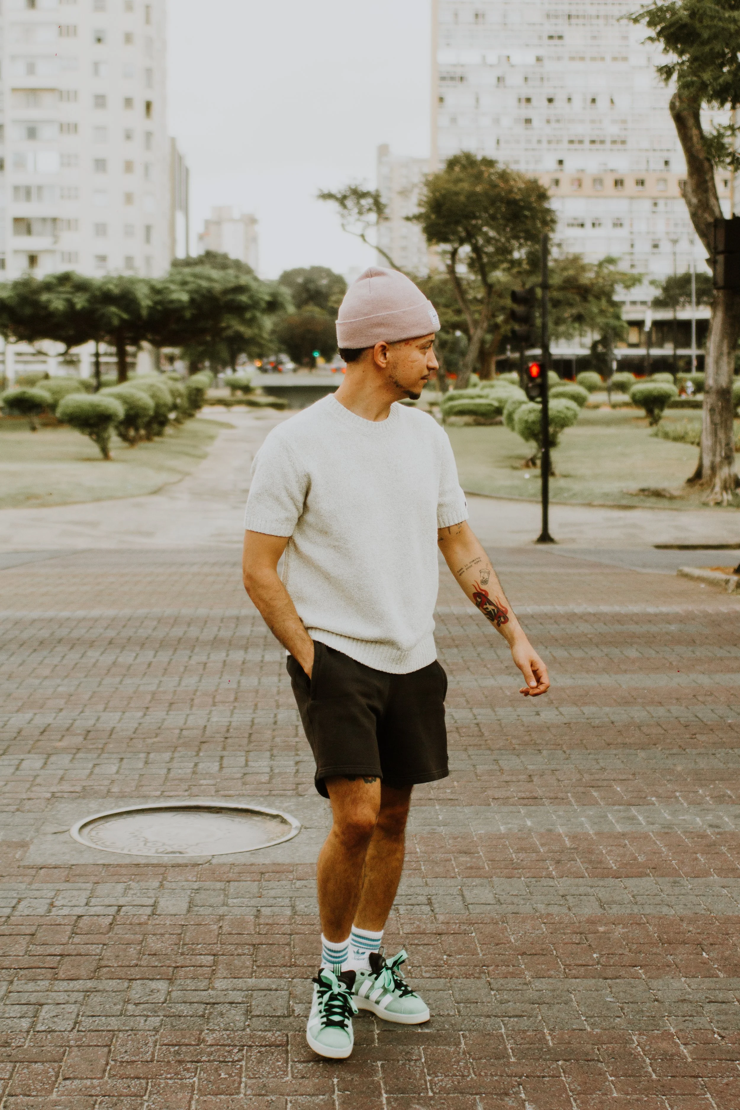 Vincent Alcântara caminhando de gorro e suéter claro entre os canteiros da Praça Raul Soares, ensaio fotográfico em Belo Horizonte