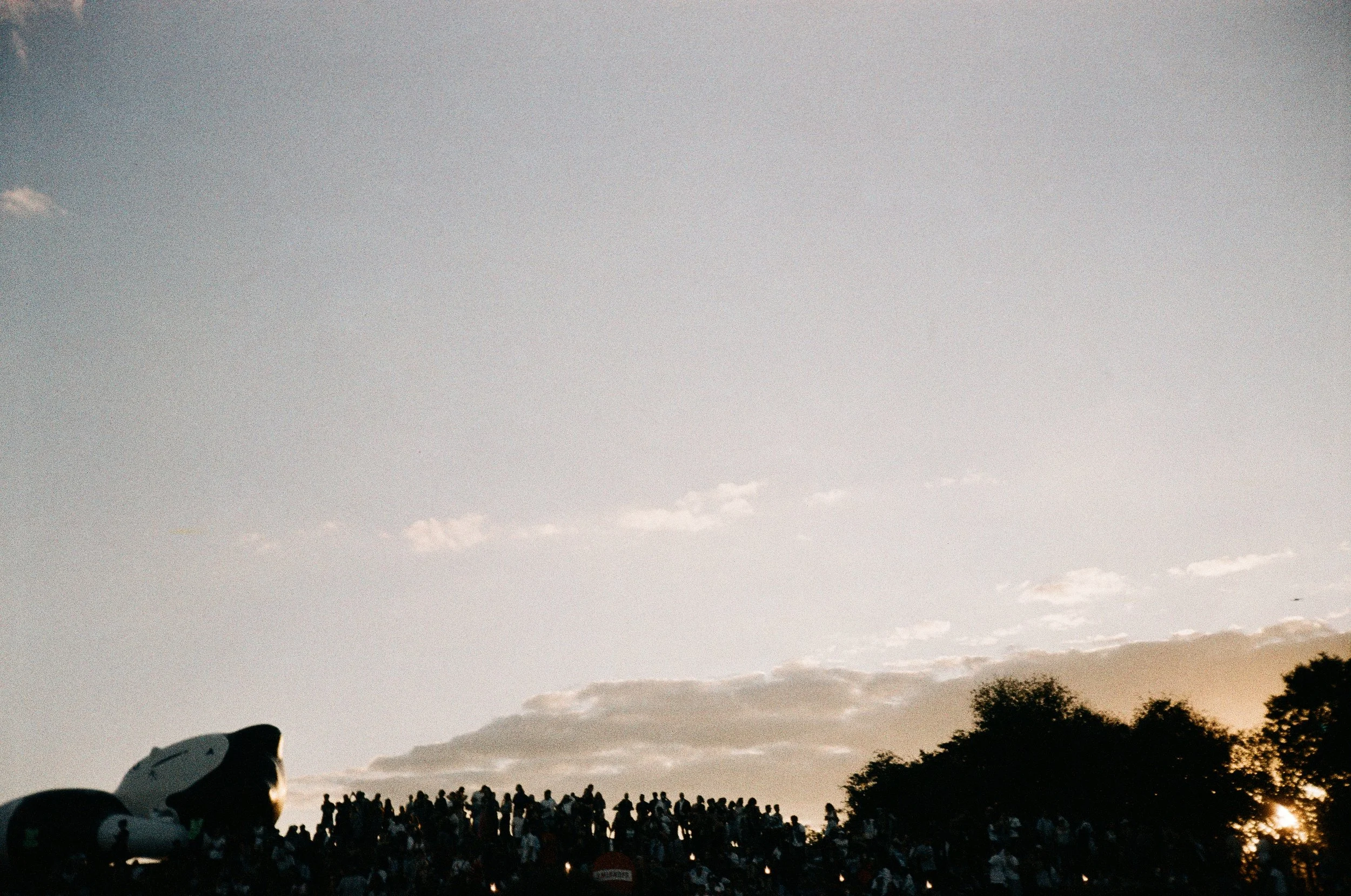 Público em silhueta contra o céu no fim da tarde durante o Festival Sensacional, fotografia analógica