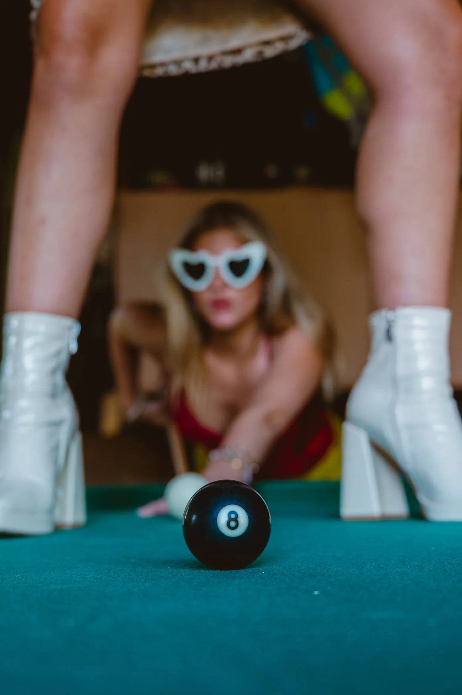 A woman in heart-shaped sunglasses and bright clothing posing for an editorial portrait