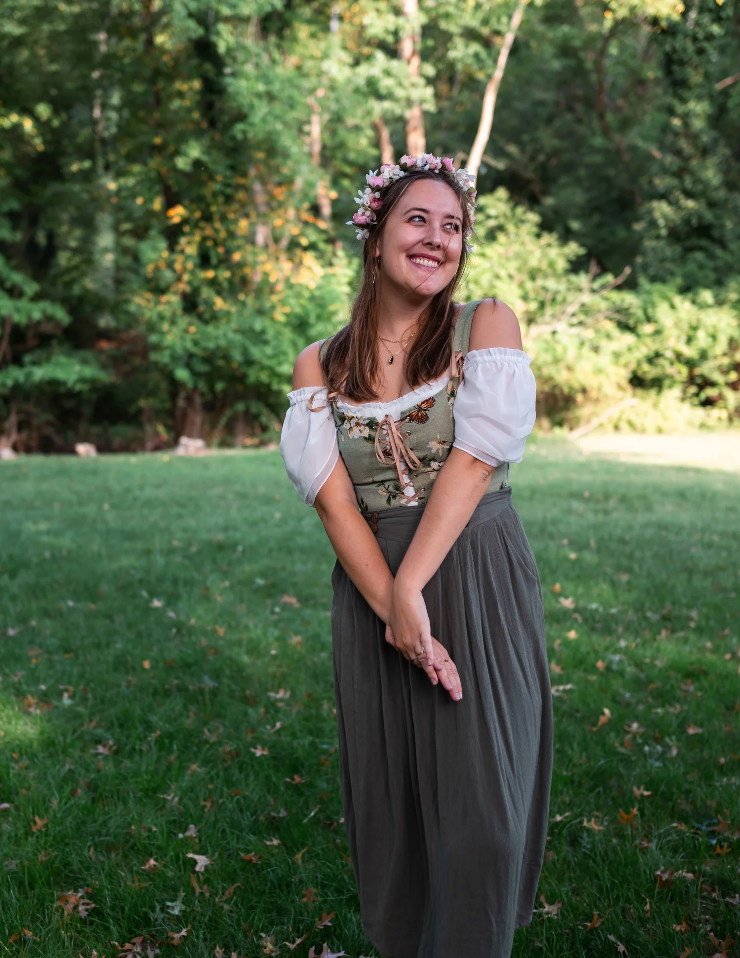 A young woman wearing a floral crown and a green off-shoulder dress