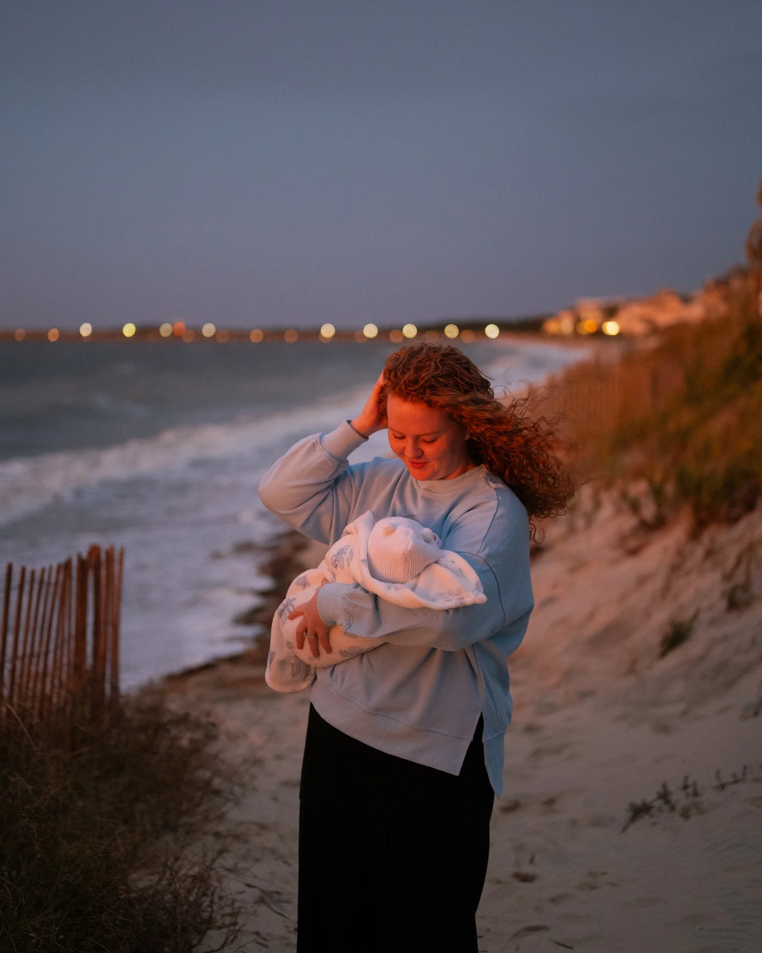 A mother holding her newborn on the beach at dusk