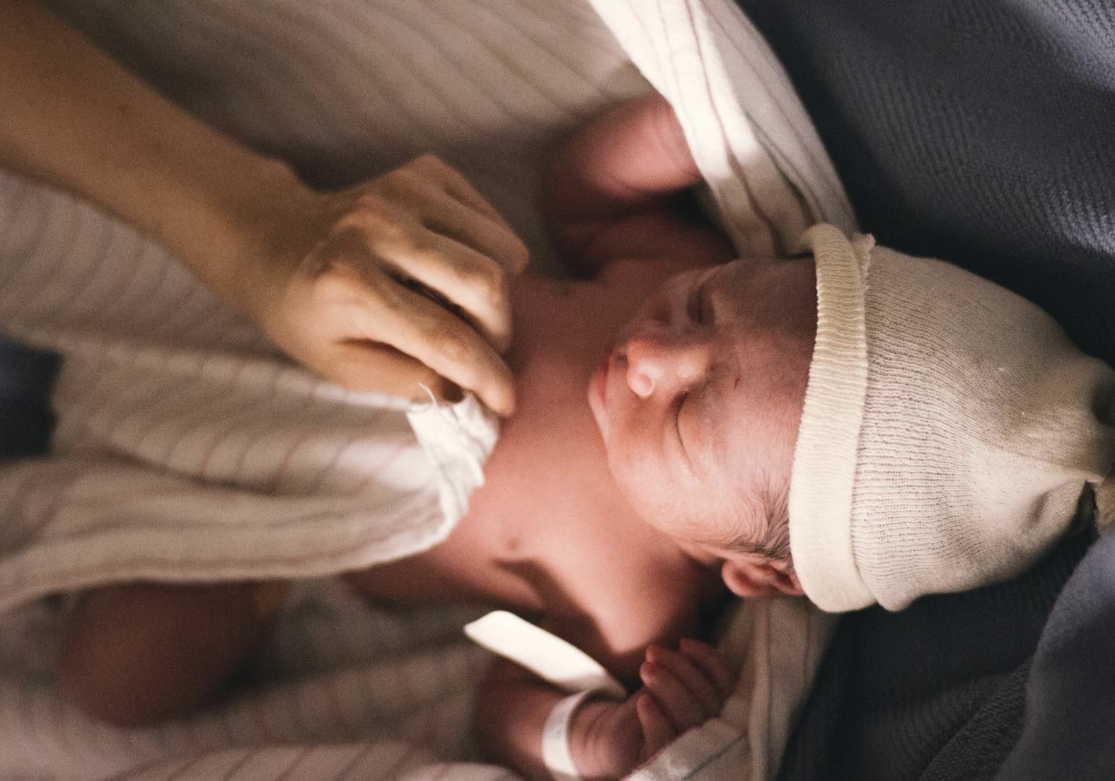 newborn baby being swaddled