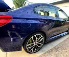 A dark blue luxury sedan parked on a street.
