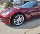Red sports car parked on the street, with a charging cable connected to it.