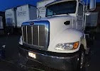 Front view of a silver semi-truck with a chrome grille, parked outdoors.
