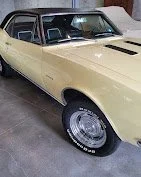 A yellow classic coupe car with black accents, parked indoors.