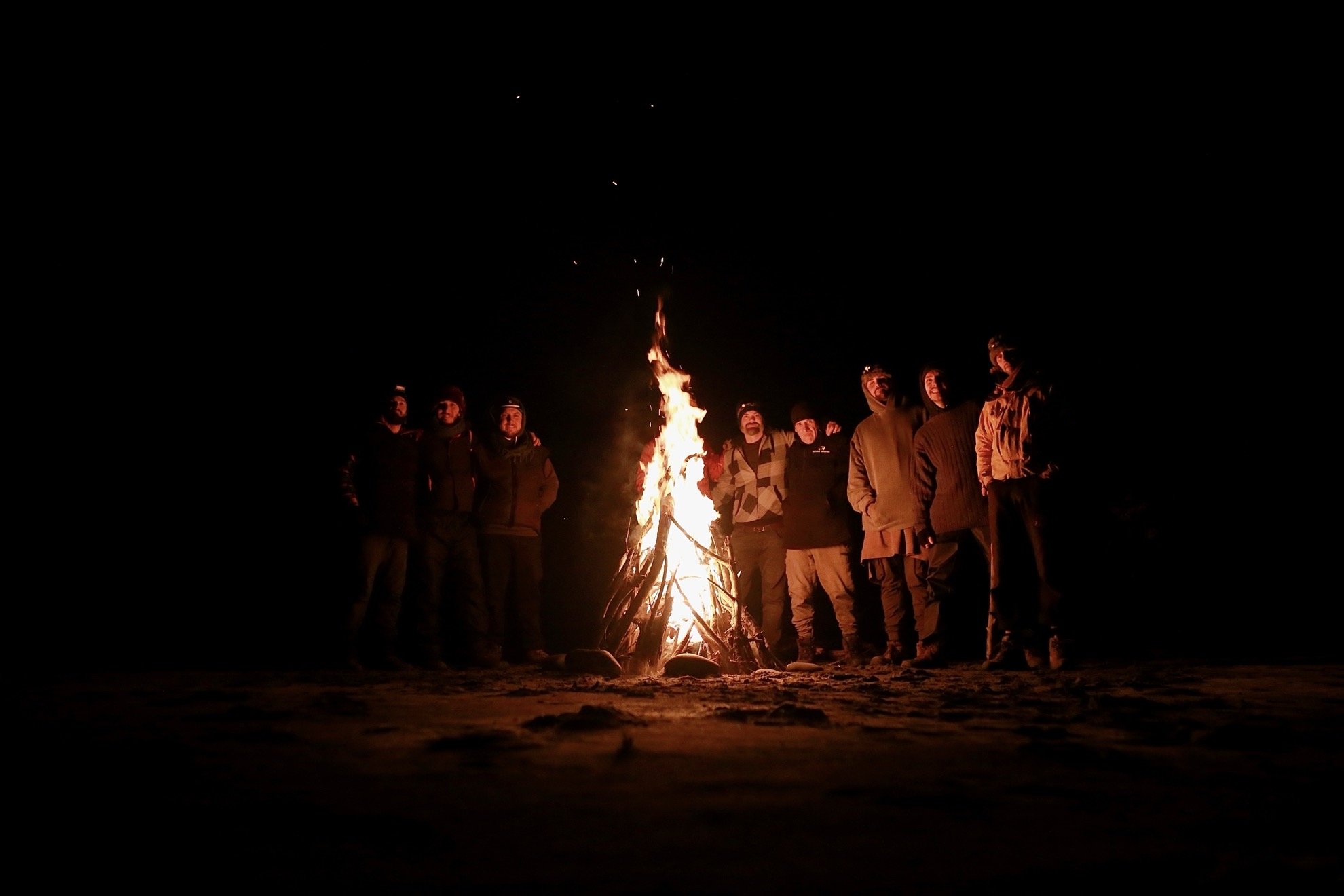 Men gathered around a campfire at a winter men's retreat in New Zealand