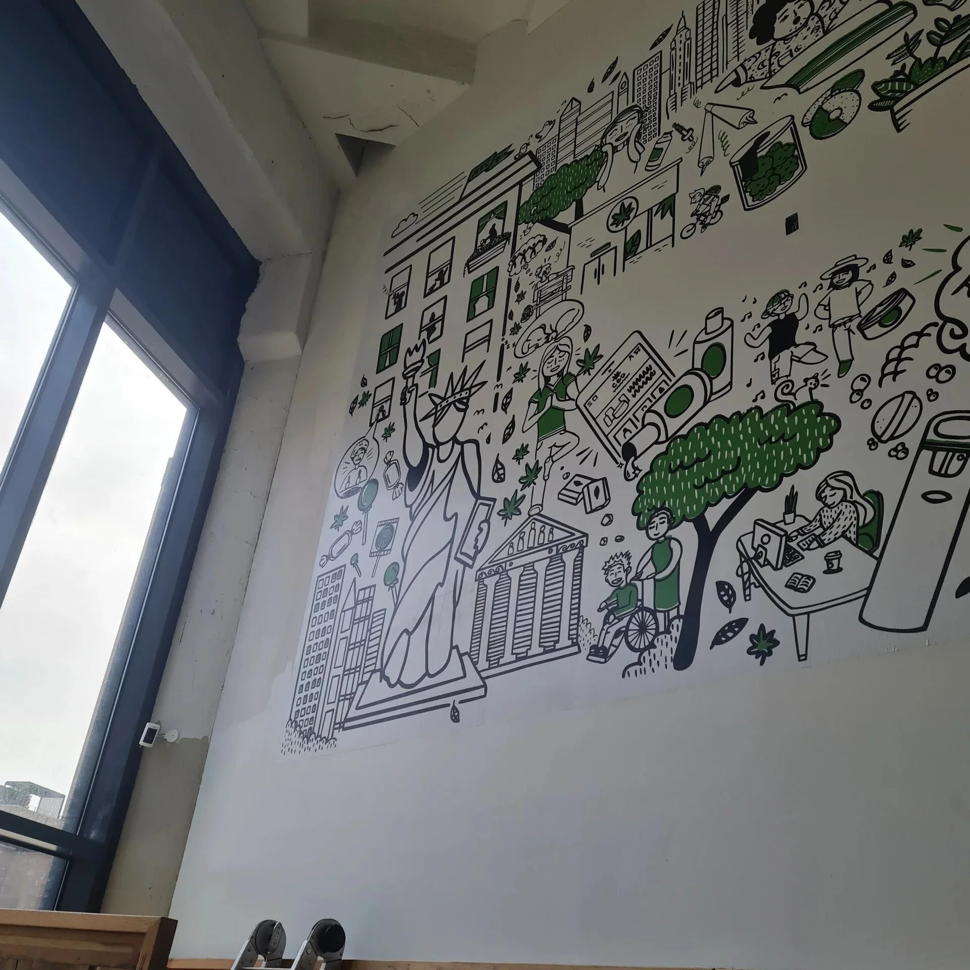 A large mural featuring various illustrations of urban life, green spaces, people gardening, working on a computer, and enjoying outdoor activities, with a depiction of the Statue of Liberty and city skyline in black, white, and green colors.