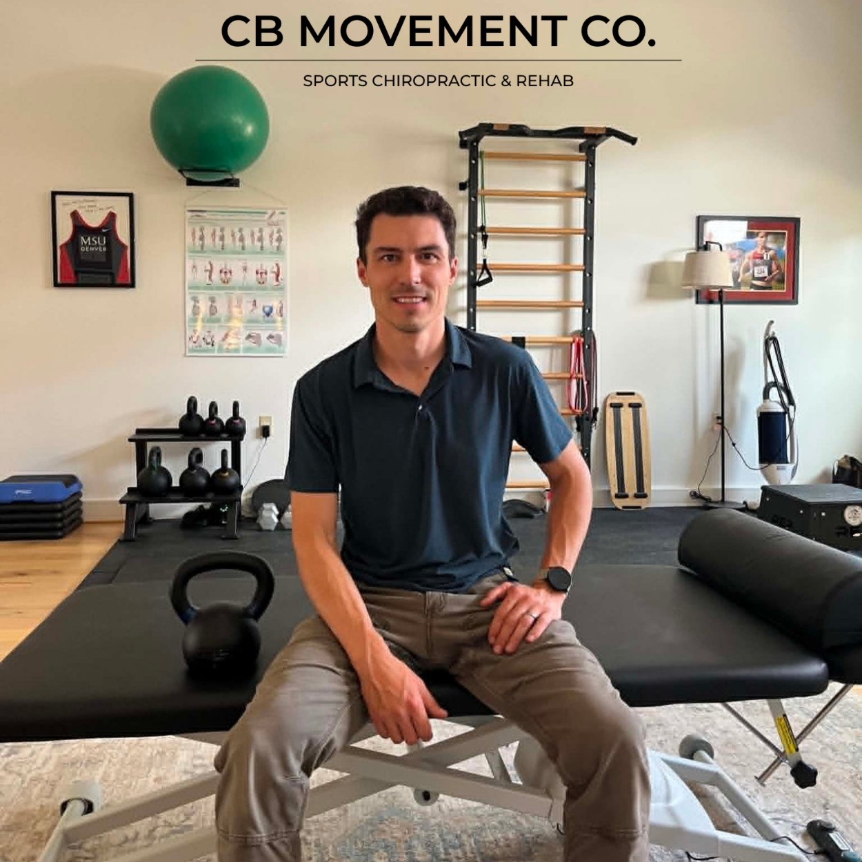 Man sitting on therapy table in a fitness or rehab room with exercise equipment and wall decorations.