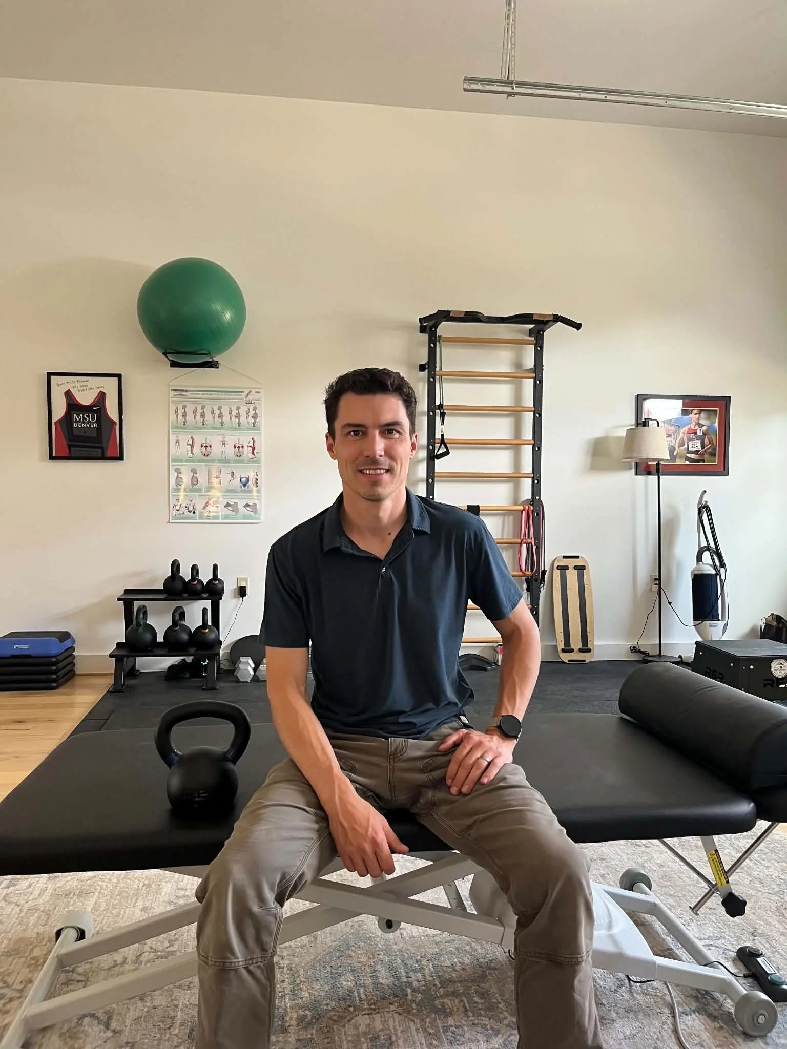 Dr Wes Rickman DC sitting on a chiropractic treatment table in his gym and clinic in Crested Butte South, Colorado.