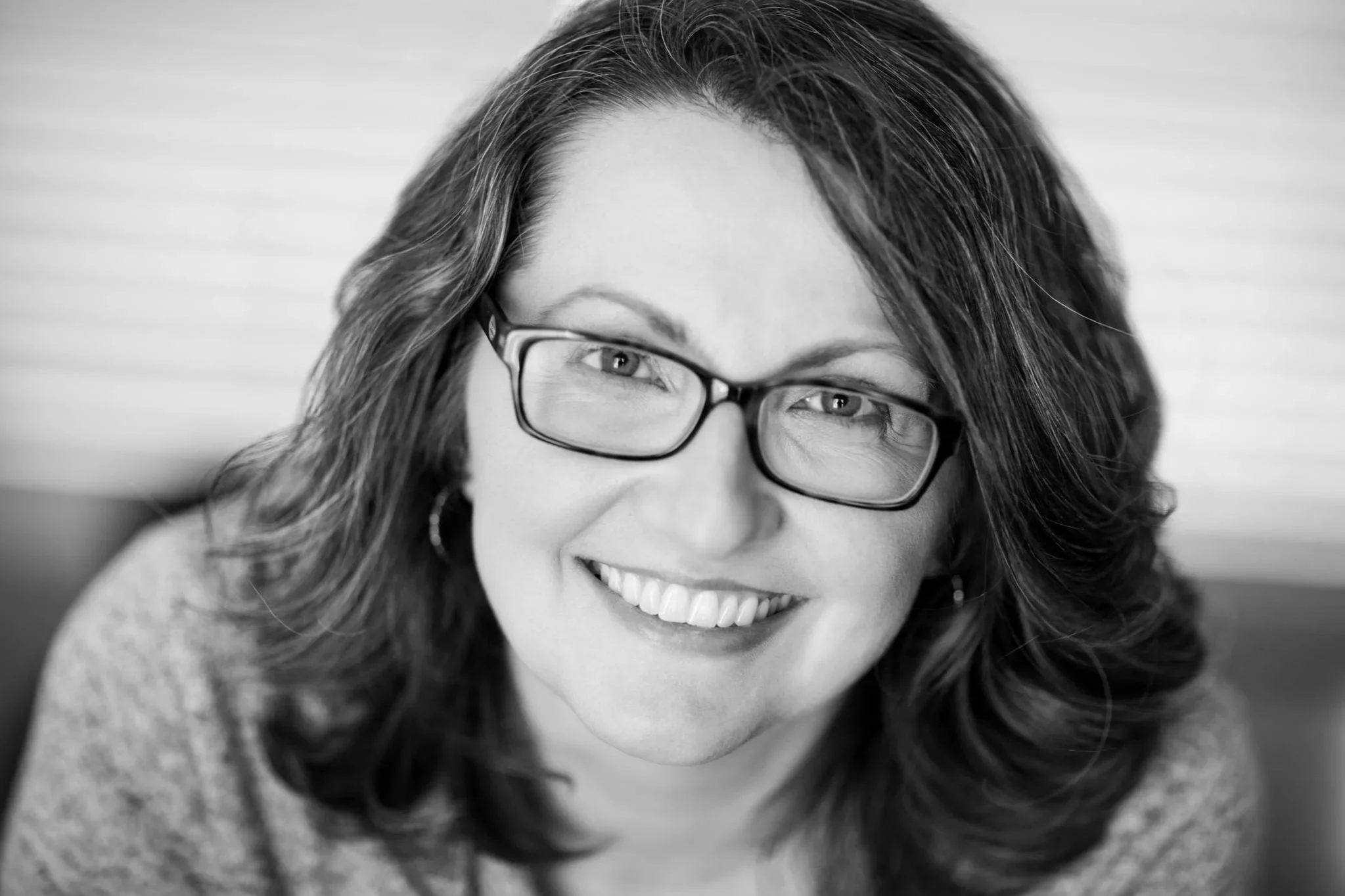 black and white photo of white woman smiling with dark hair and dark glasses