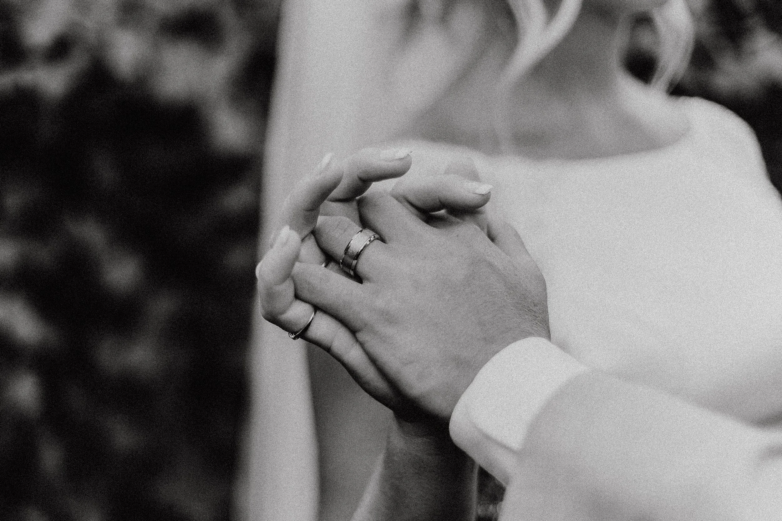 Close-up of two hands with wedding rings, gently touching each other.