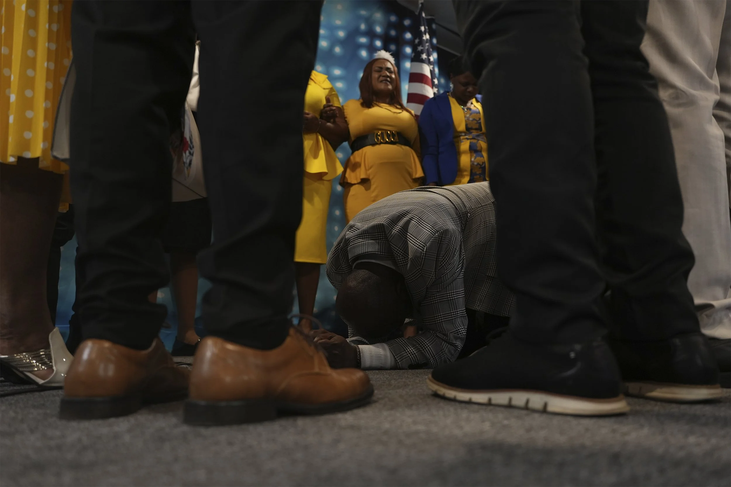 Rev. Reginald Silencieux kneels to pray, surrounded by the choir and worship team at the First Haitian Evangelical Church of Springfield, Sunday, January 26, 2025, in Springfield, Ohio. (AP Photo/Luis Andres Henao)