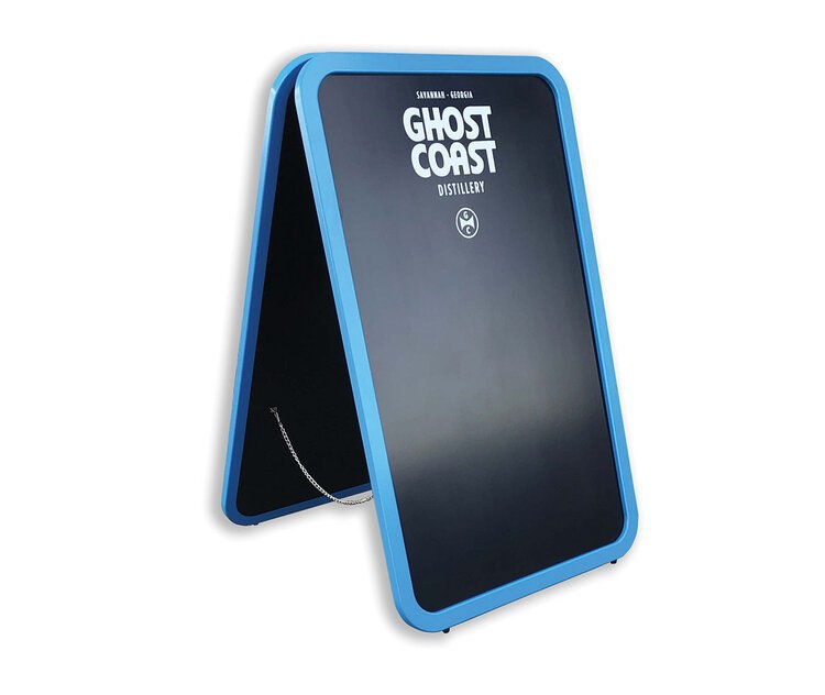 Blue A-frame sidewalk signboard with a black surface displaying the text 'GHOST COAST DISTILLERY' and a small logo beneath, standing on a white background.