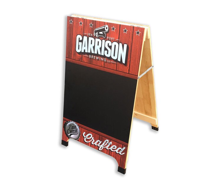 A wooden sandwich board sign with a red wood grain design, displaying the Garrison Brewing Co. logo with a cannon, and the words Crafted at the bottom, used for advertising outside a business.