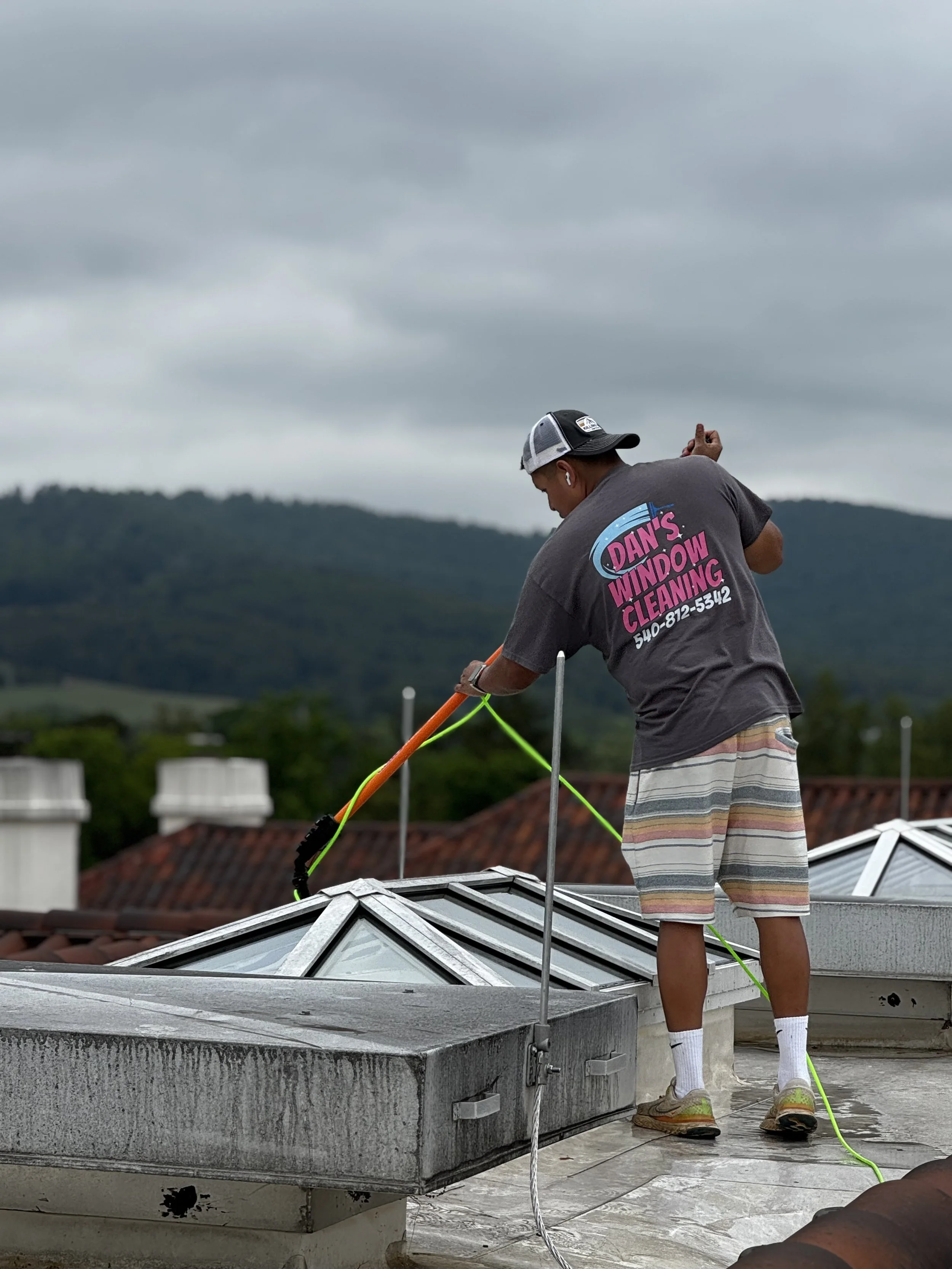 Man uses professional window cleaning equipment to clean the glass skylights on the roof of a hotel resort building located in Keswick, Virginia.