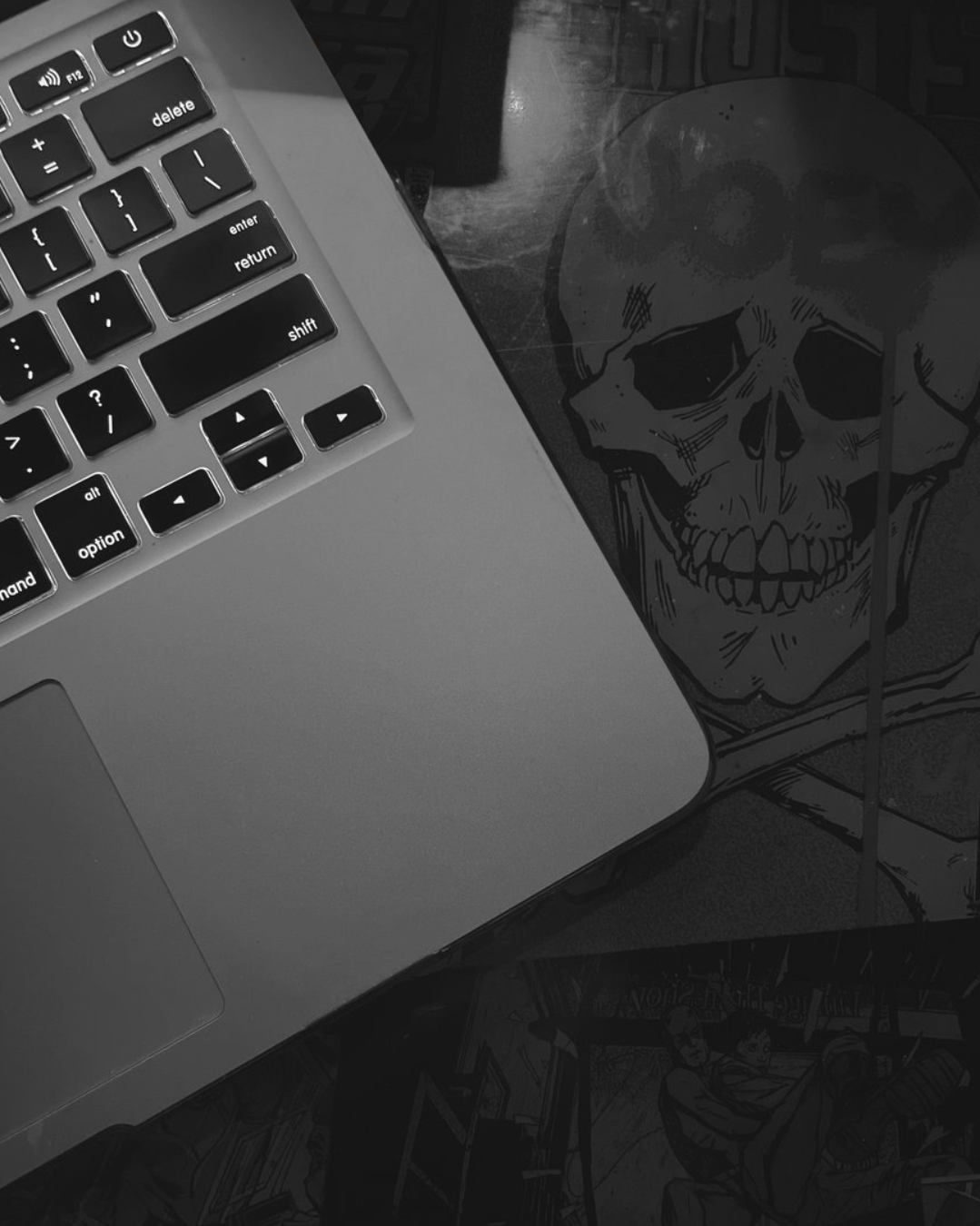a laptop open at a bar, only the keyboard is visable and there is a skeleton inlayed on the table.