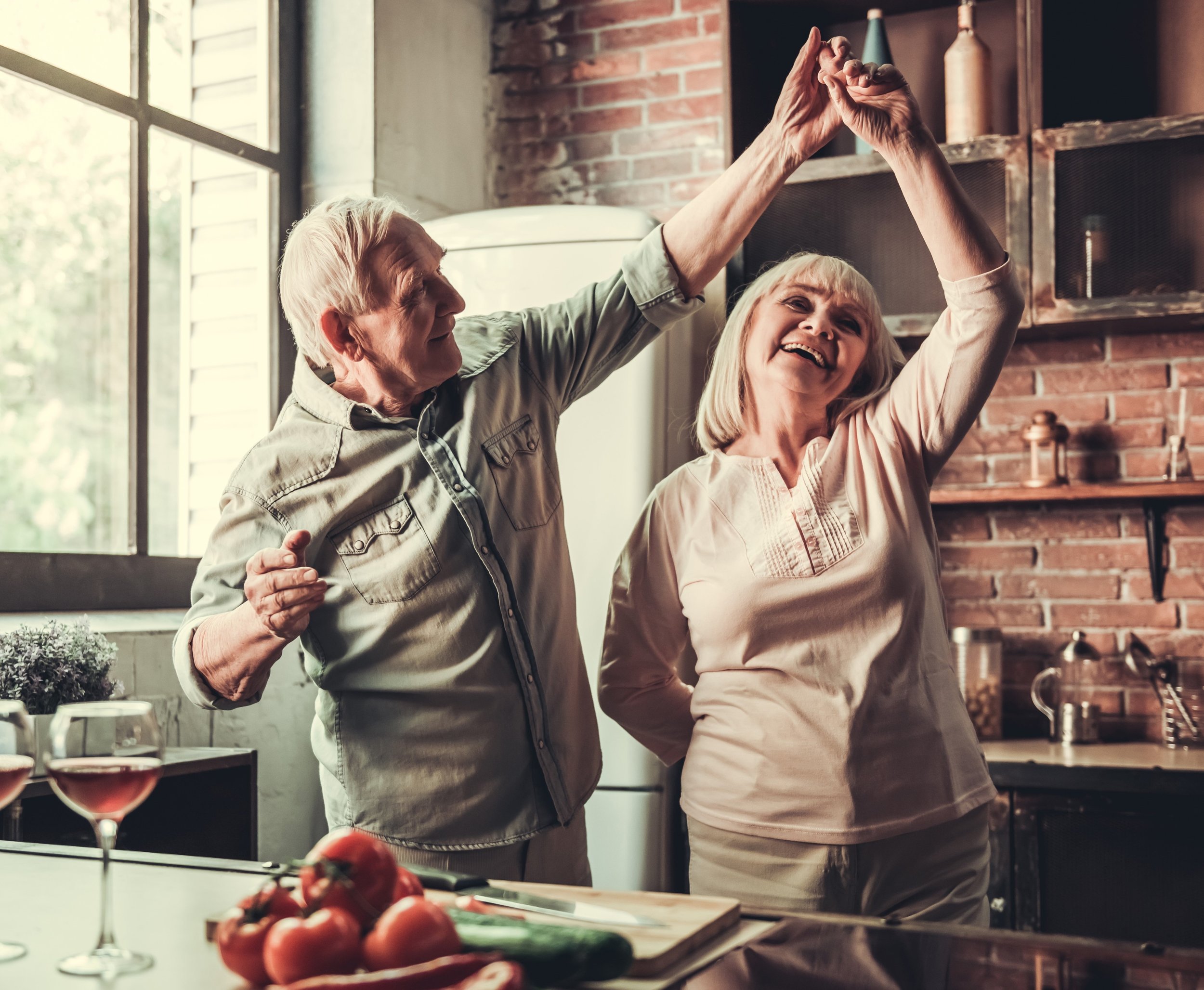 happy elderly couple dancing in kitchen