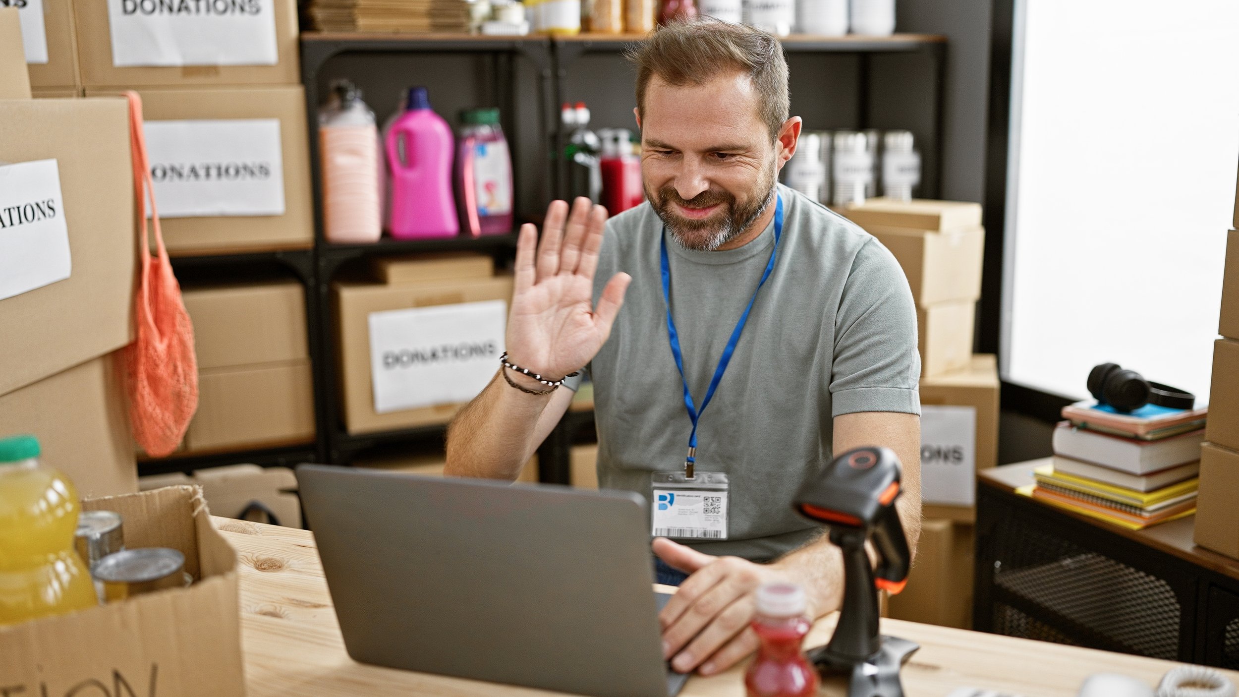 smiling Latino man in back office greets someone online