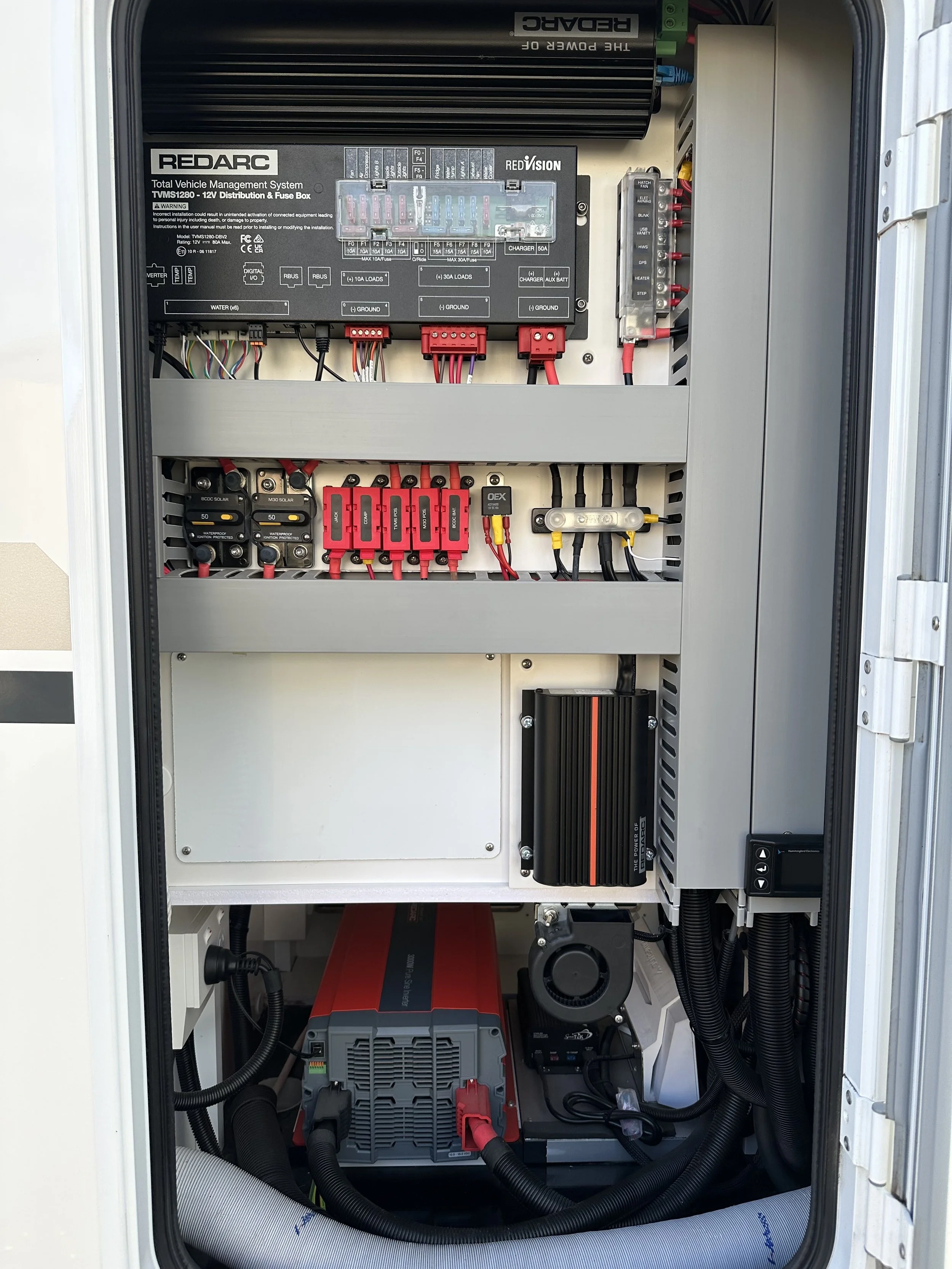 Electrical control panel with various components including circuit breakers, wires, and a power inverter.