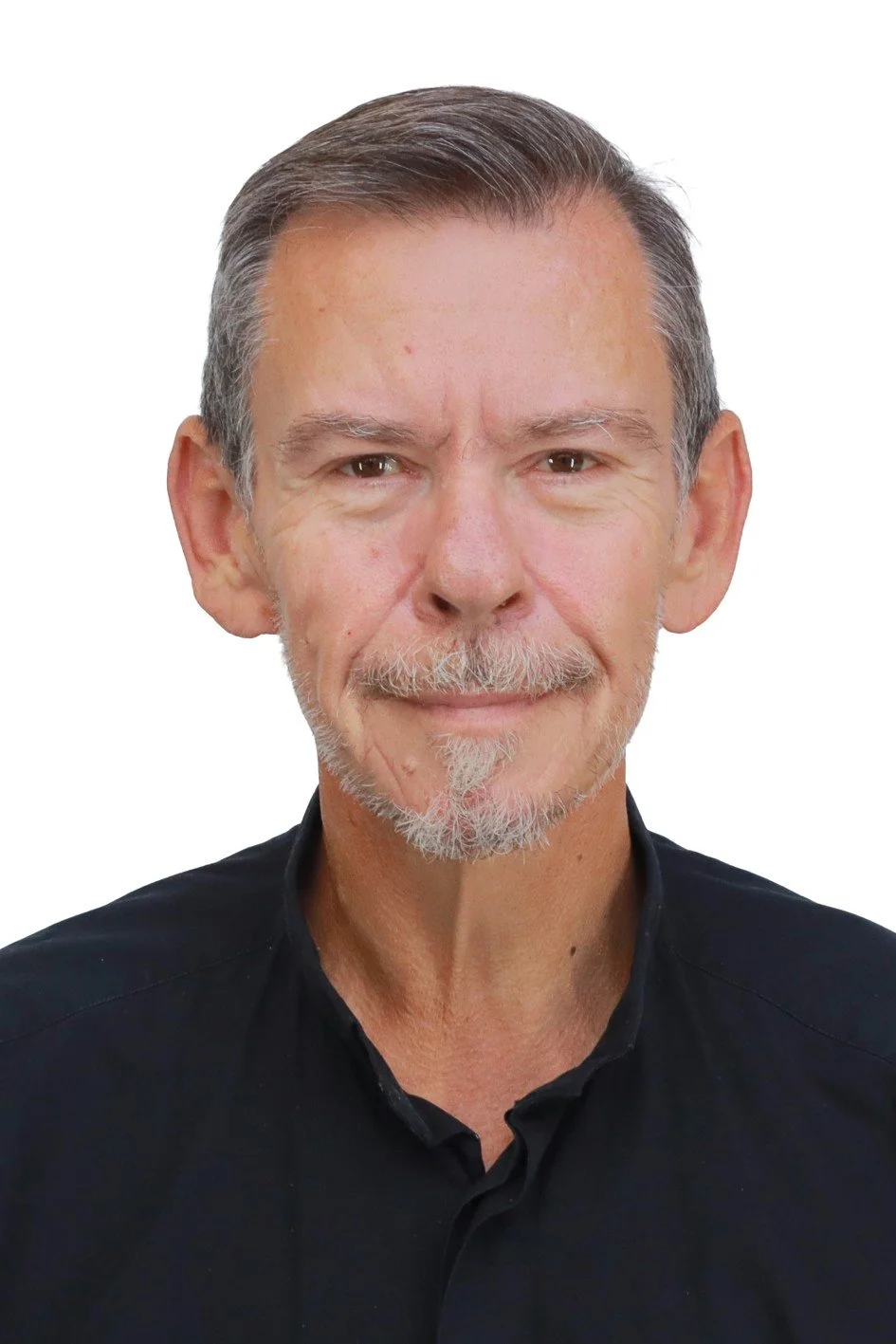 Close-up portrait of a middle-aged man with short gray hair, a gray goatee, and wearing a black shirt, smiling slightly against a plain white background.