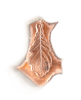A small carved stone or clay artifact resembling a leaf with an intricate carved central vein pattern.