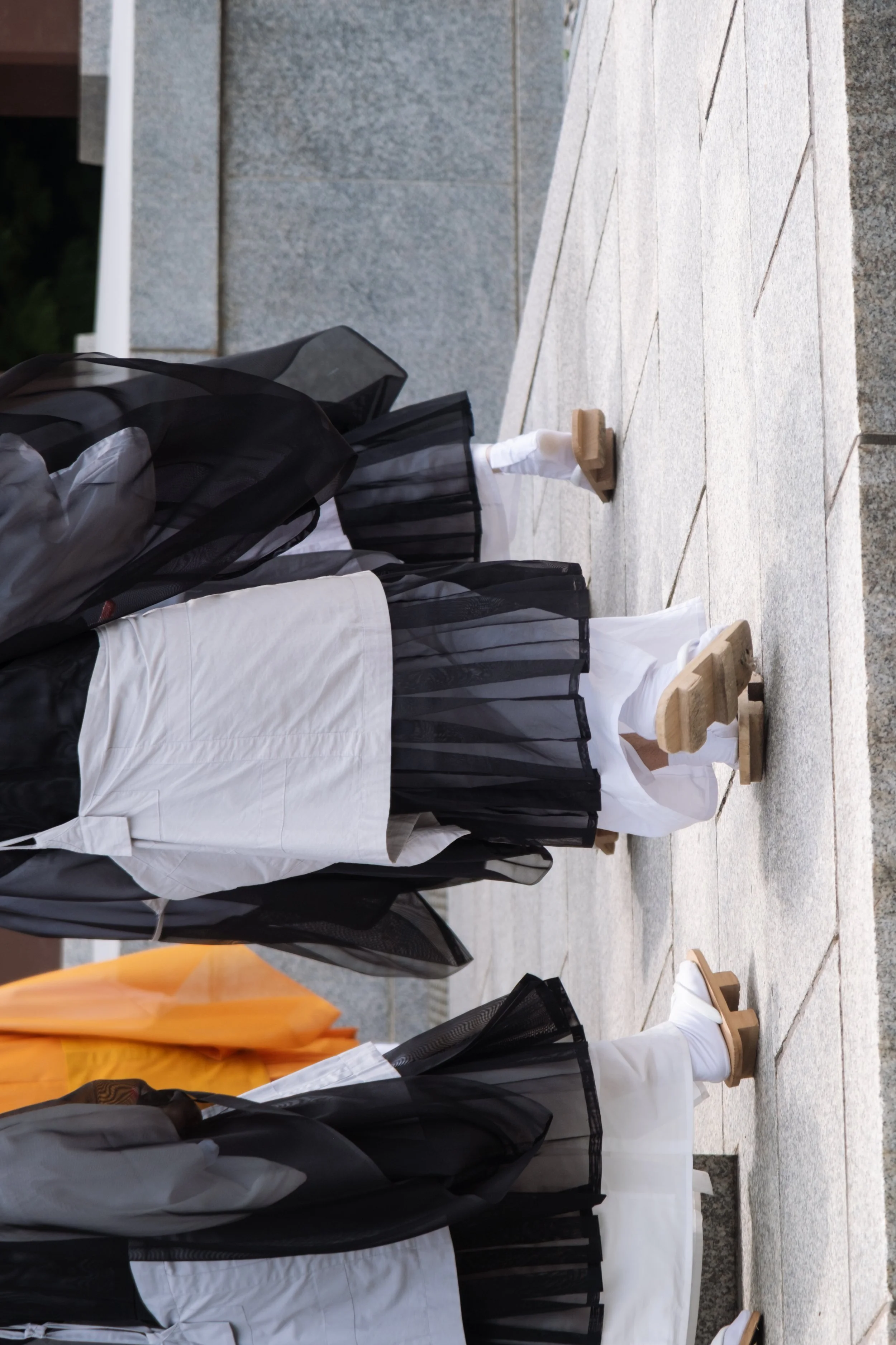 People dressed in traditional clothing standing on a stone pavement.
