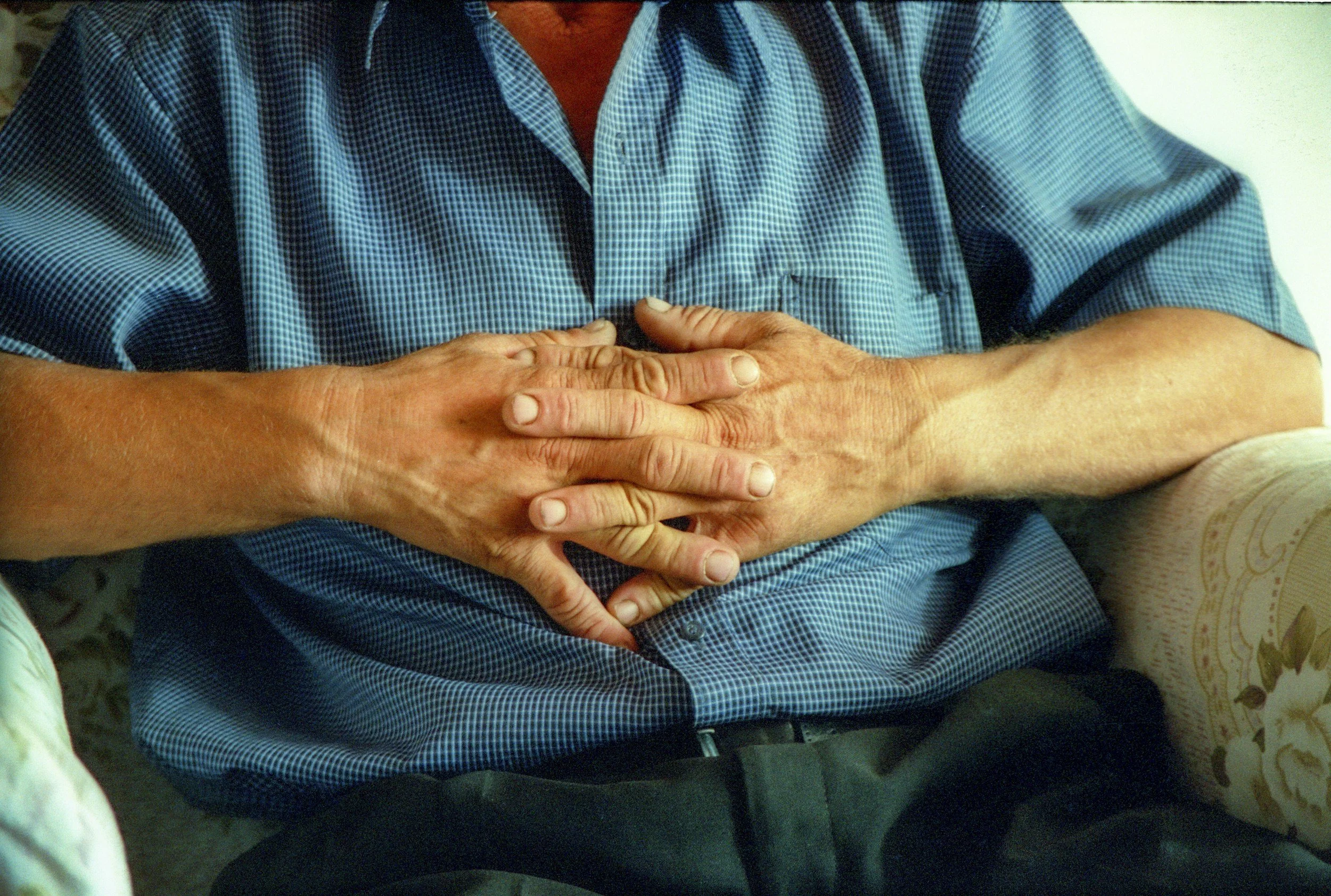 Man with hands folded and blue shirt