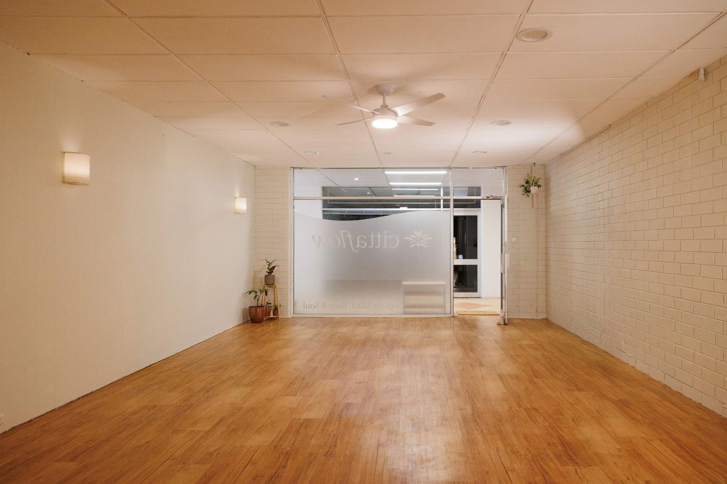 calm neutral yoga studio with frosted glass windows, and timber floor
