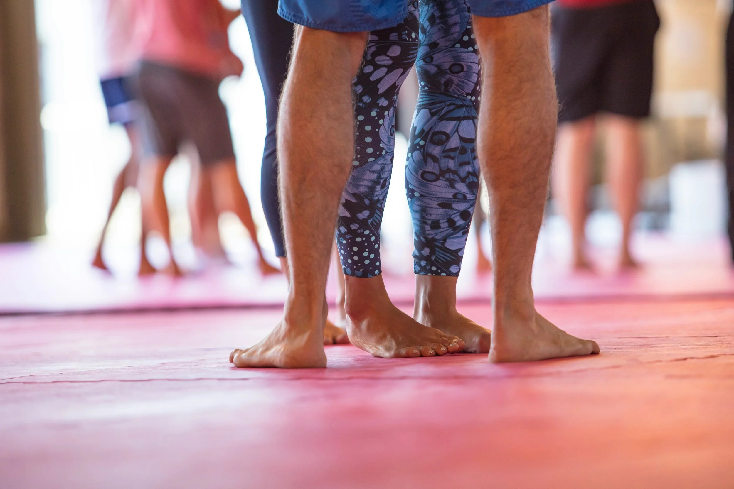 Men and women doing yoga on pink floor