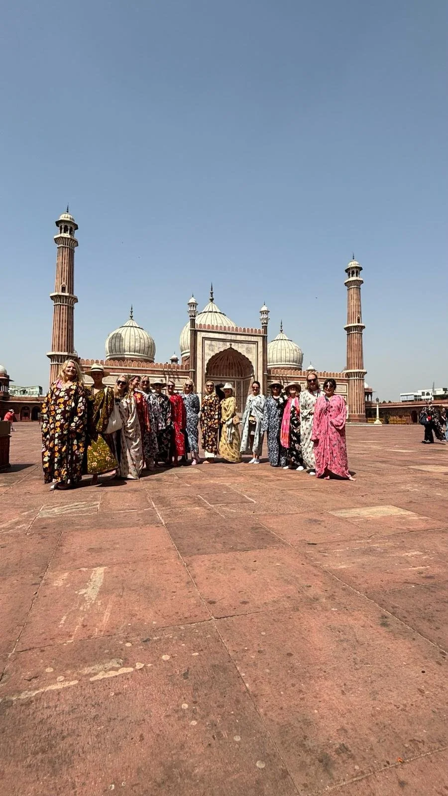 A group of women in colorful traditional dresses standing in front of the Taj Mahal in India.