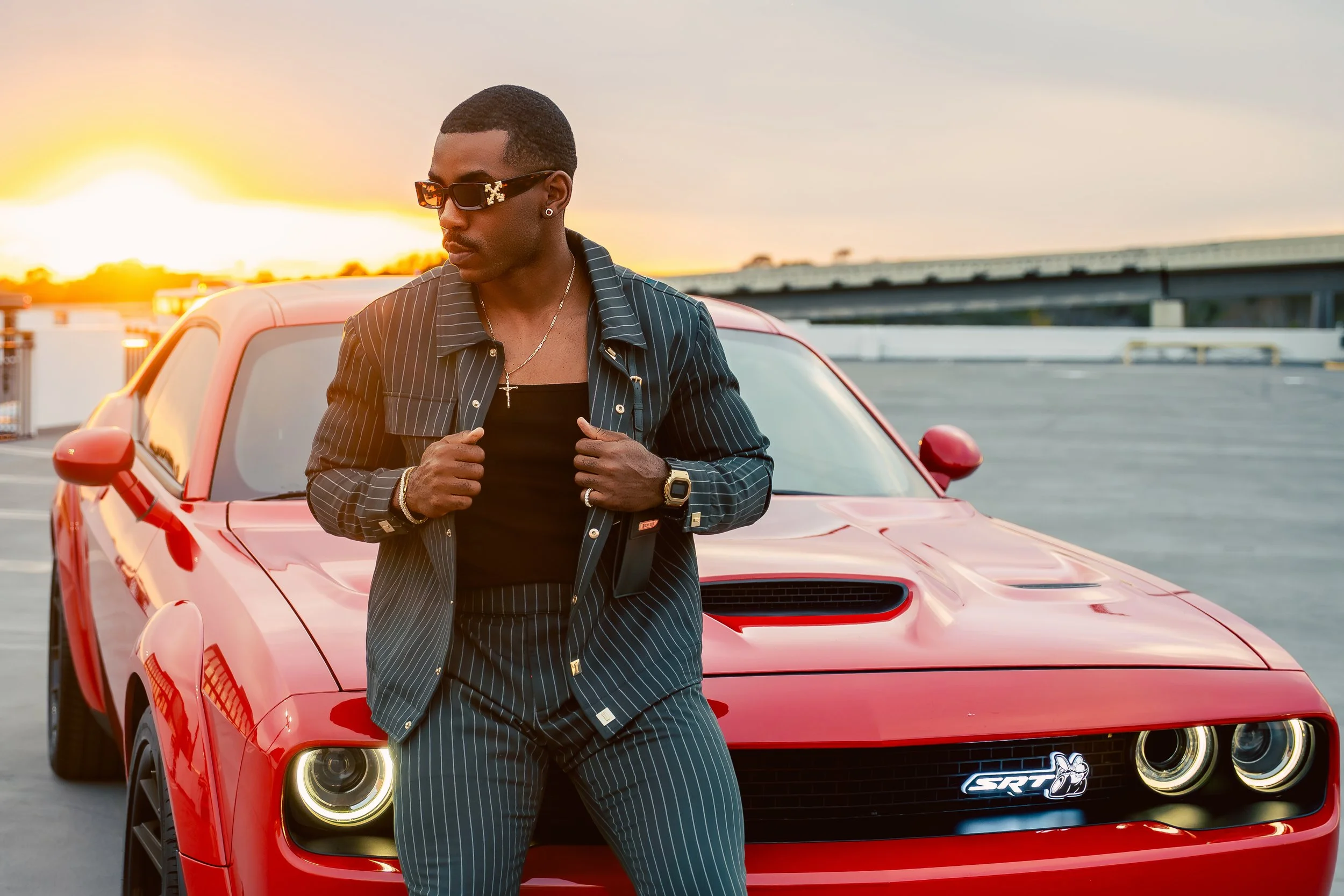Man leaning on a red Dodge Challenger at golden hour in Houston, still from a spec commercial by Macanthony Studios