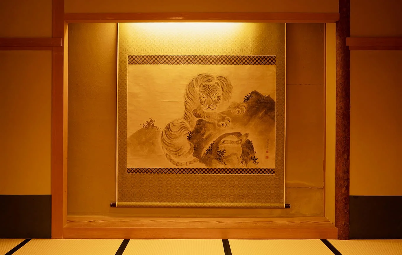 伝統的な日本の部屋に飾られた絵画。虎の絵が中心で、山の風景と草木を描いている。
