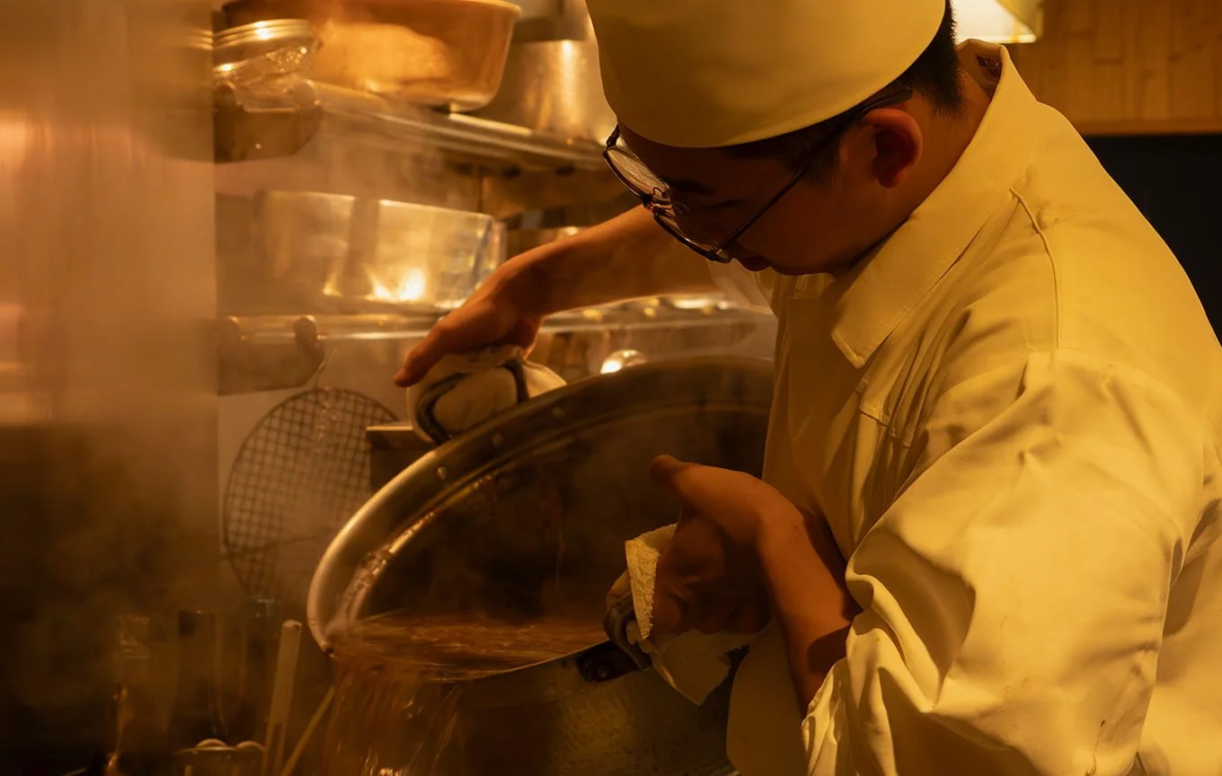 シェフが鍋の中の料理を調理しているキッチンのシーン