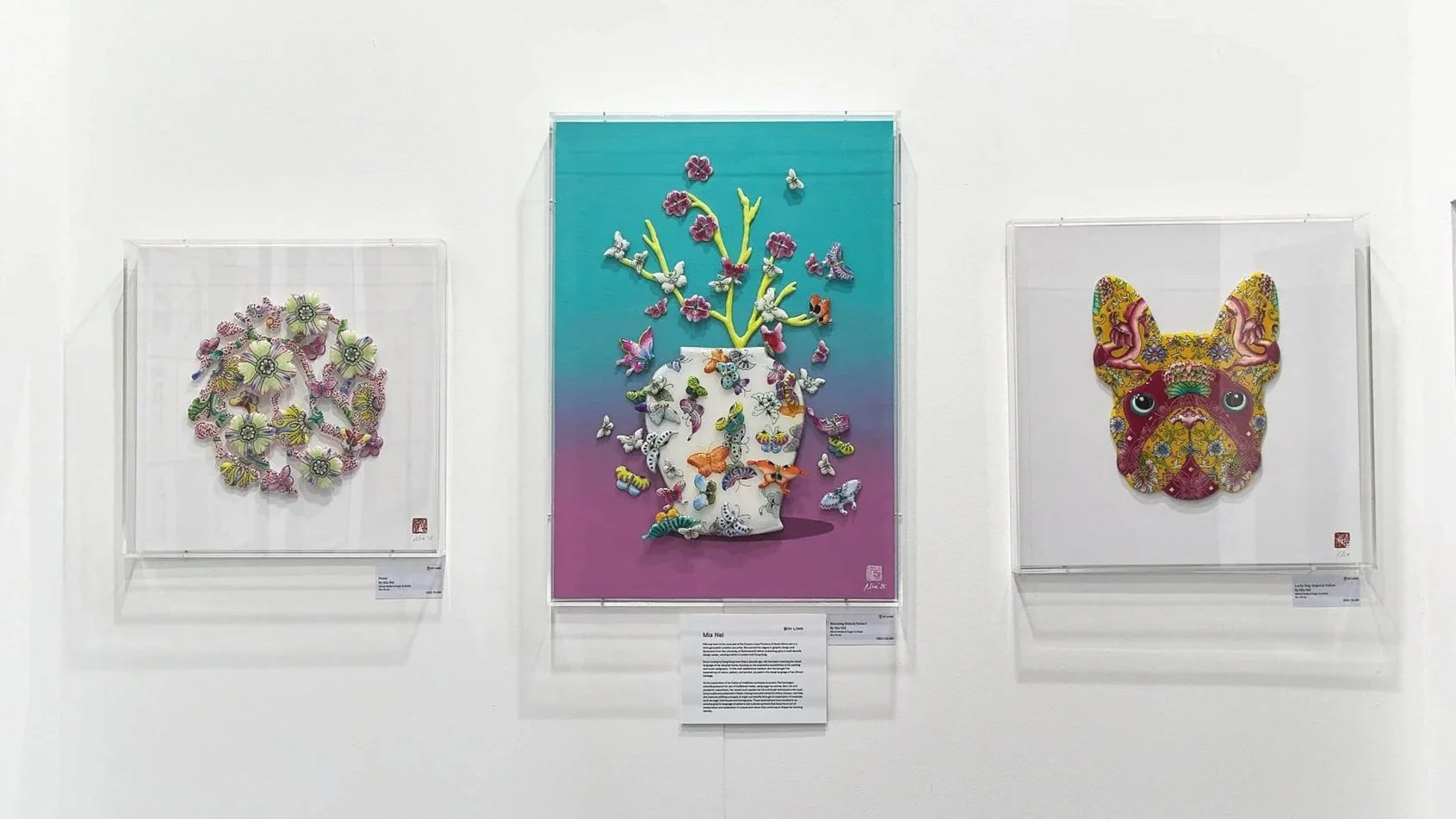 Art Central 2025: Three framed artworks on a white gallery wall, featuring colorful intricately designed butterfly, crown made of flowers, and a dog face with ornate patterns.