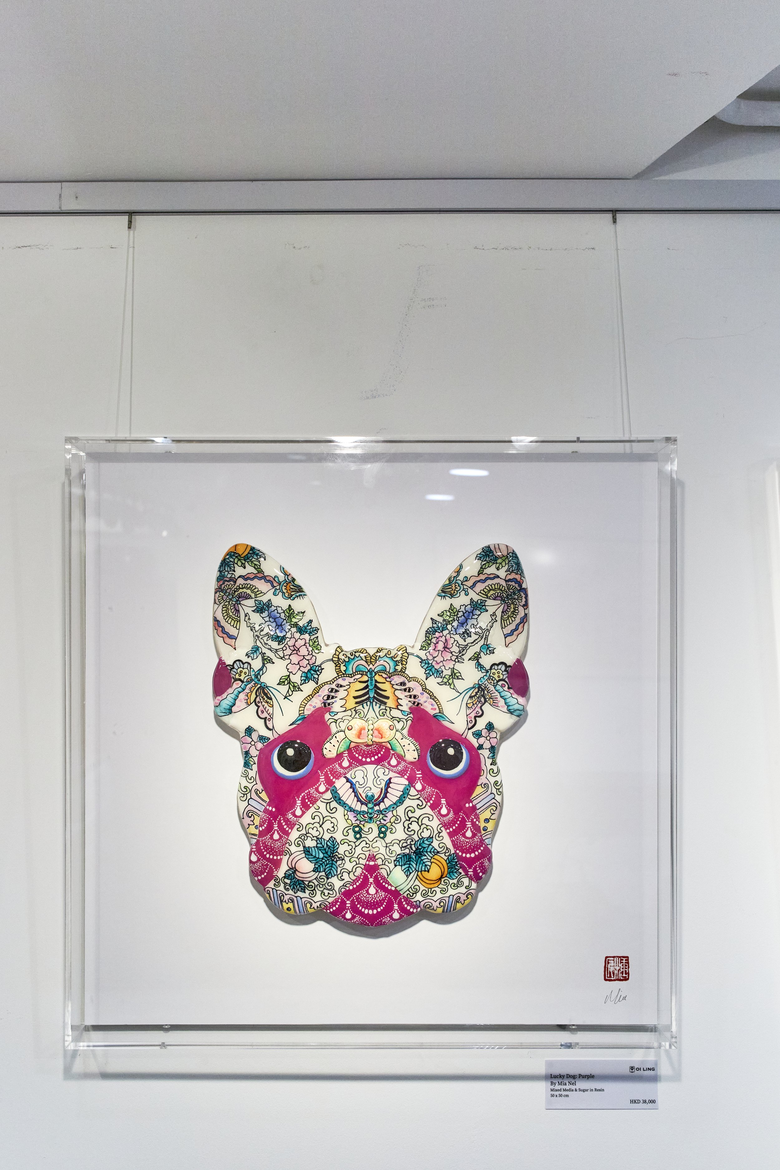 Colorful artwork of a French Bulldog's face with intricate floral and abstract patterns, displayed in a glass frame.