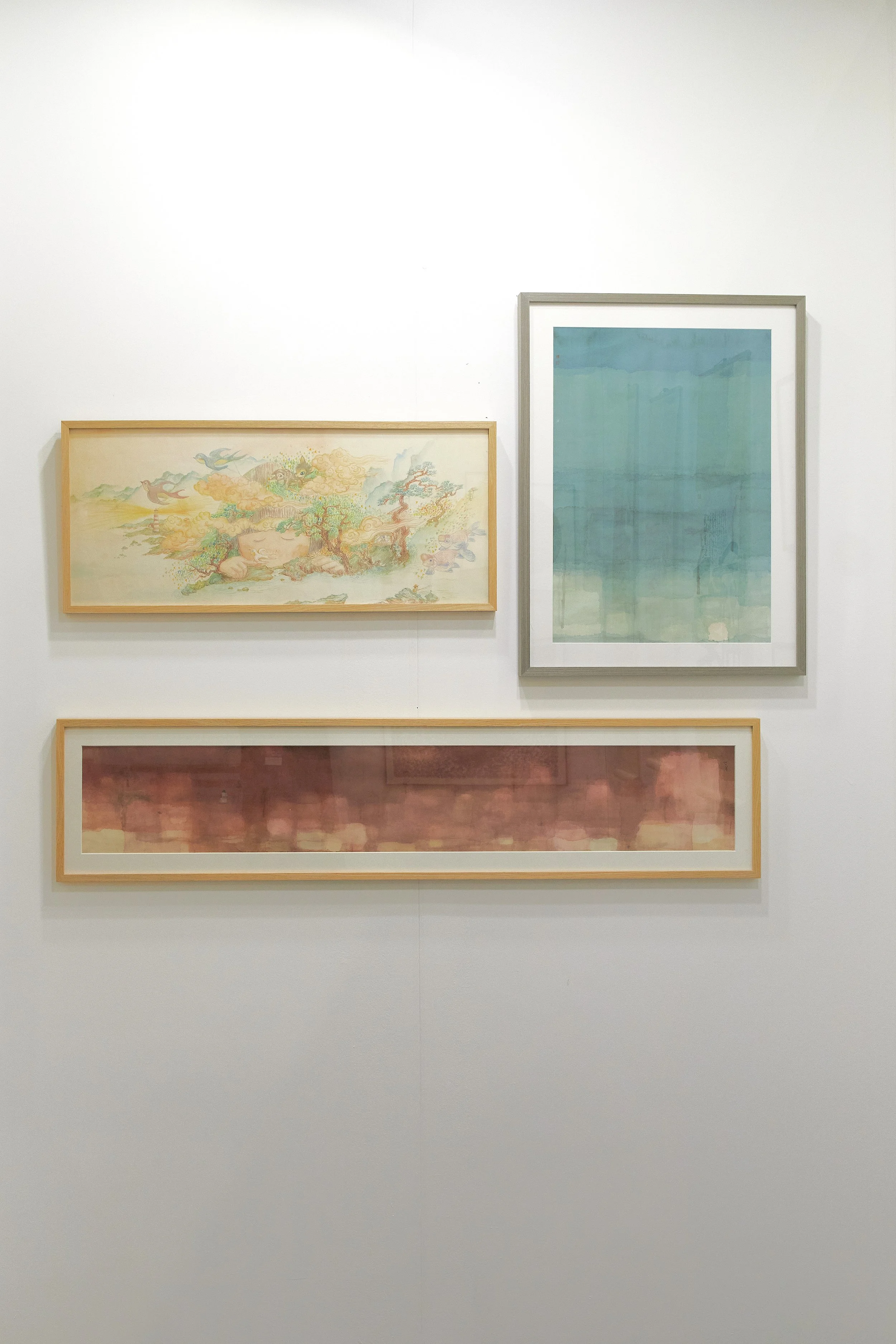 Affordable Art Fair 2025: Three framed artworks displayed on a white gallery wall, with two smaller horizontal pieces and one larger vertical piece.