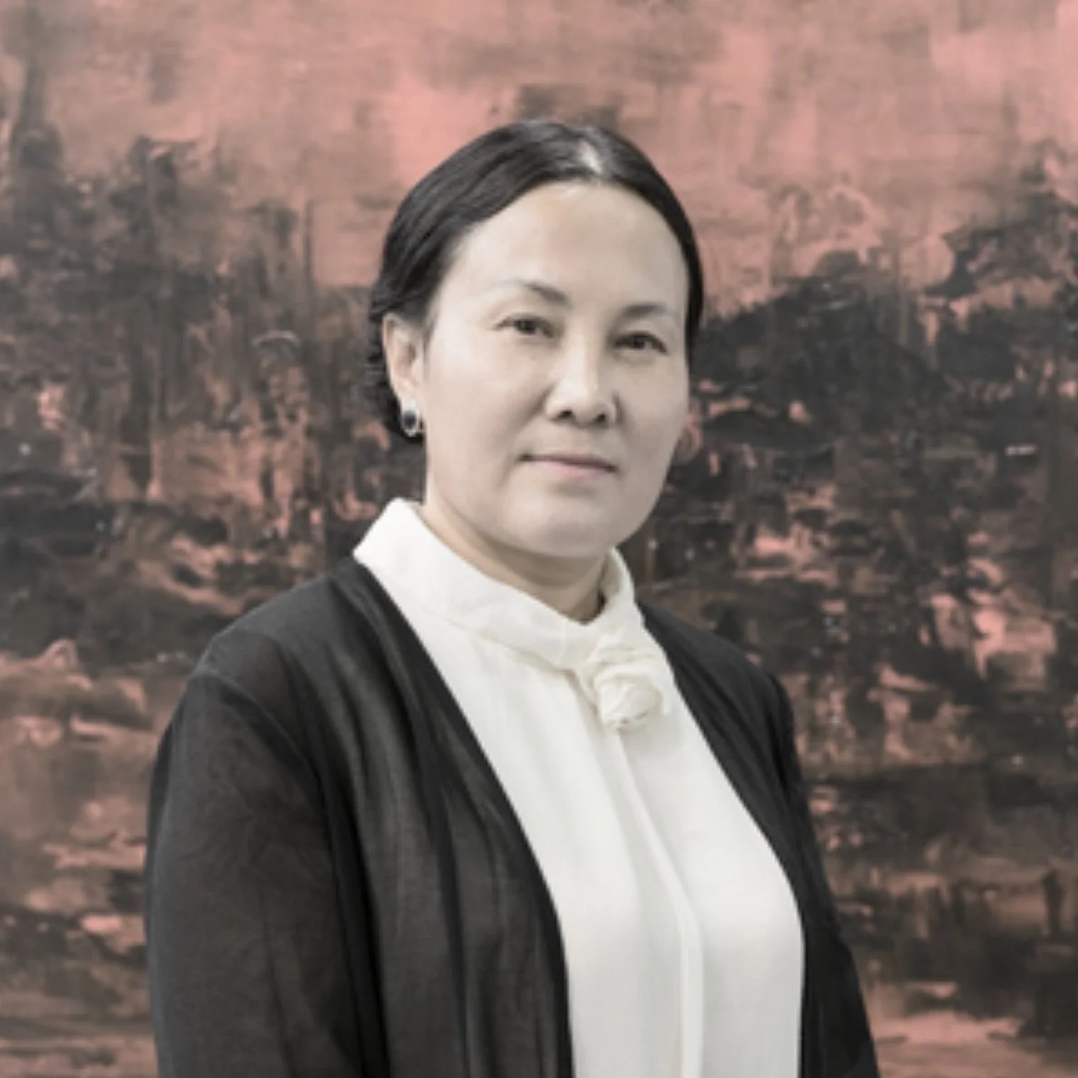 Zhou Lianhua 周連華：A woman with black hair and earrings, wearing a black blazer over a white high-neck blouse, standing in front of an abstract red and black background.