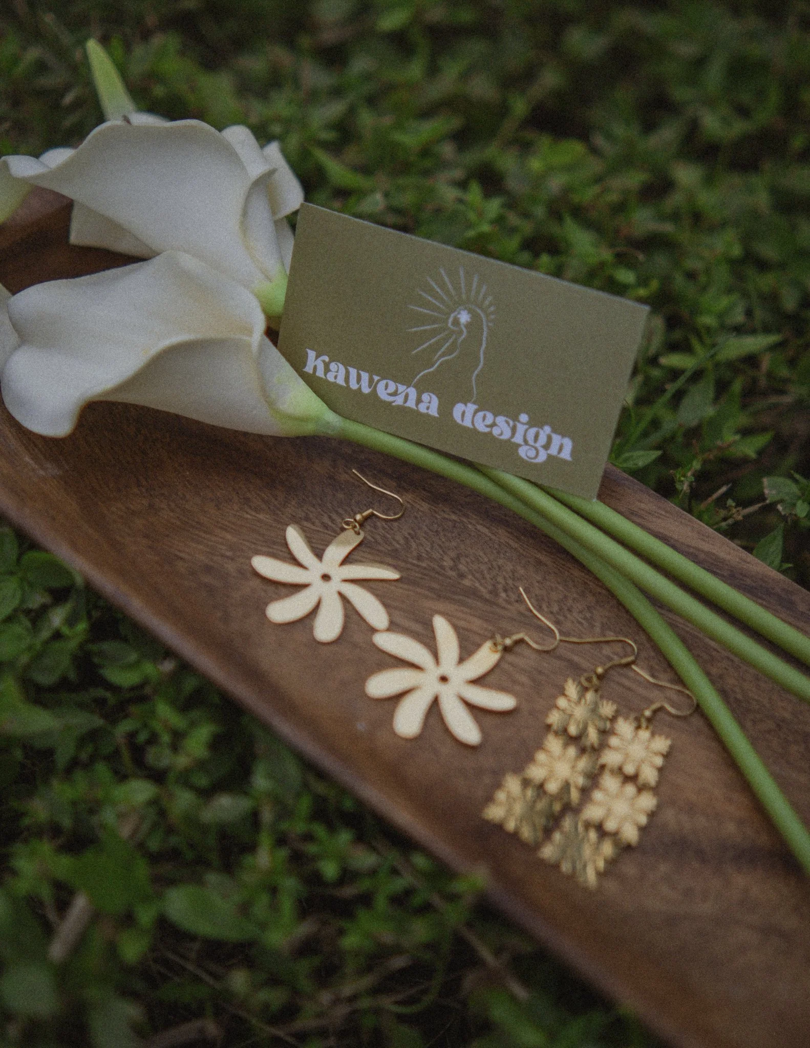 Ulu Charms earrings beautifully styled on a wooden tray with calla lilies and Kauvena Design branding.