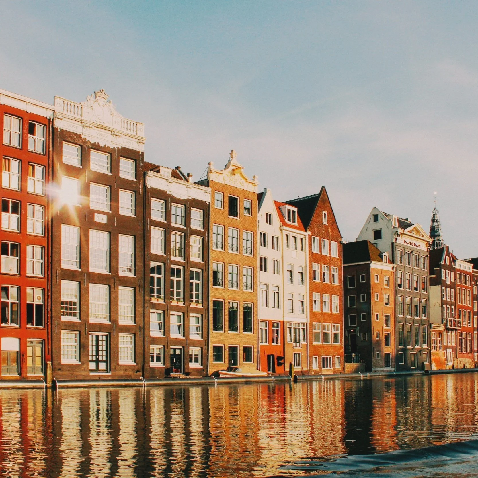 Canal-side buildings in Amsterdam with narrow facades and traditional Dutch architecture.